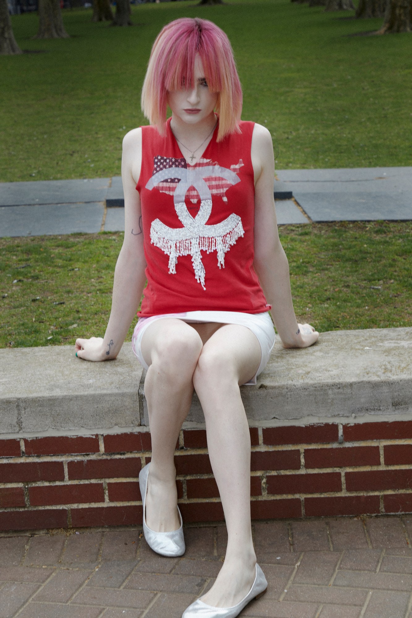 ren g of club eat sitting on a brick wall wearing a red chanel t-shirt