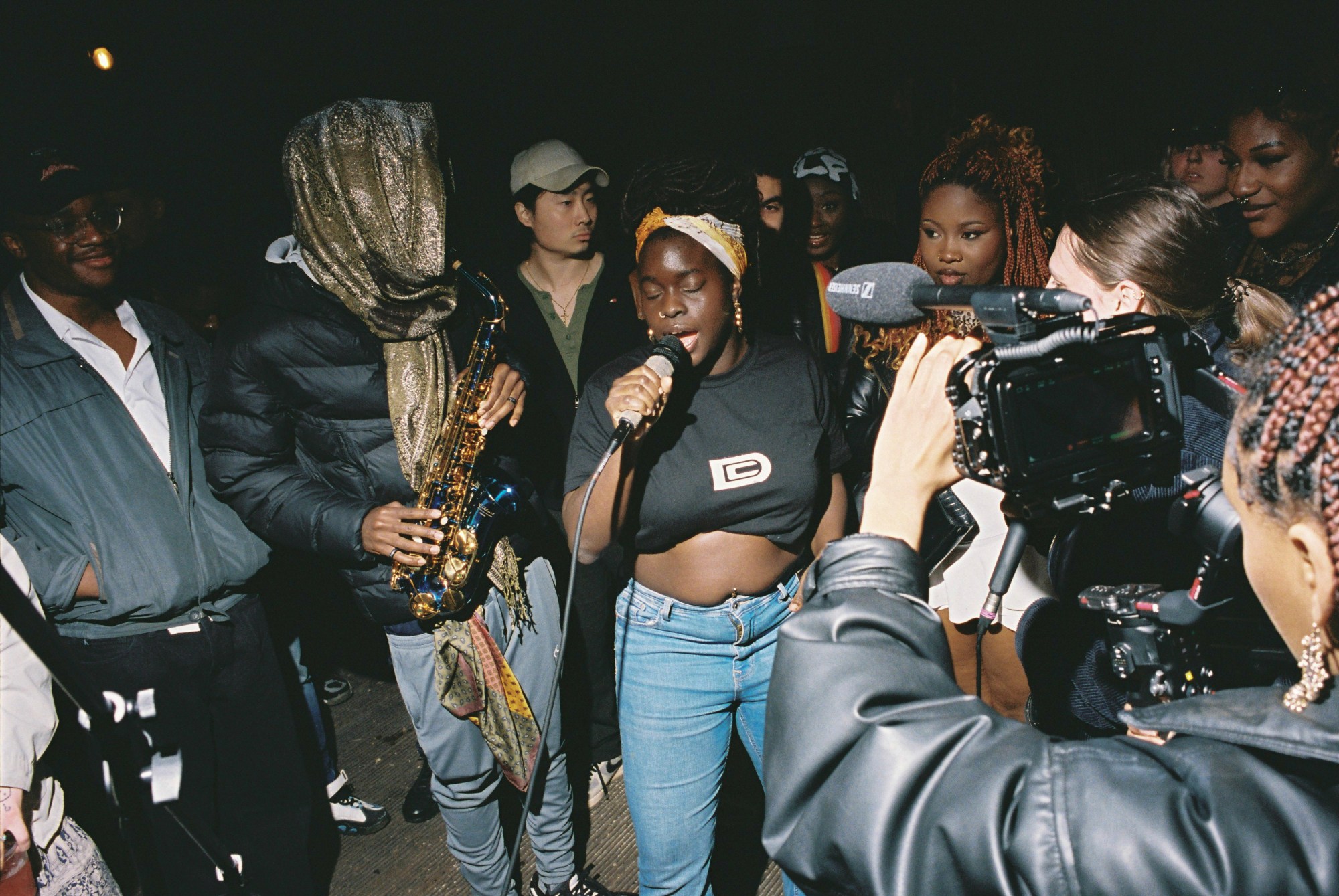 someone singing into a microphone in front of a camera at da community event in london