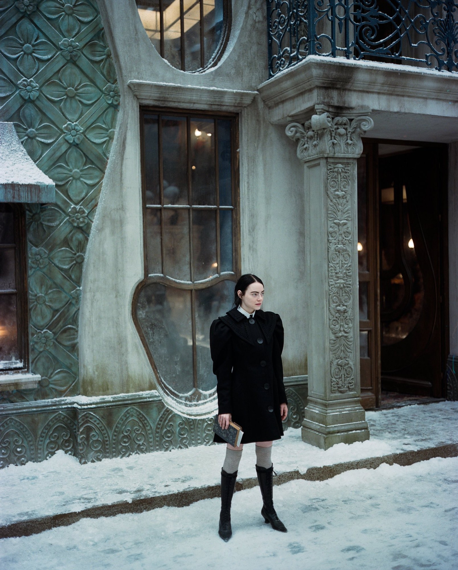 emma stone in poor things, standing in a snowy street, wearing a puff sleeved black dress