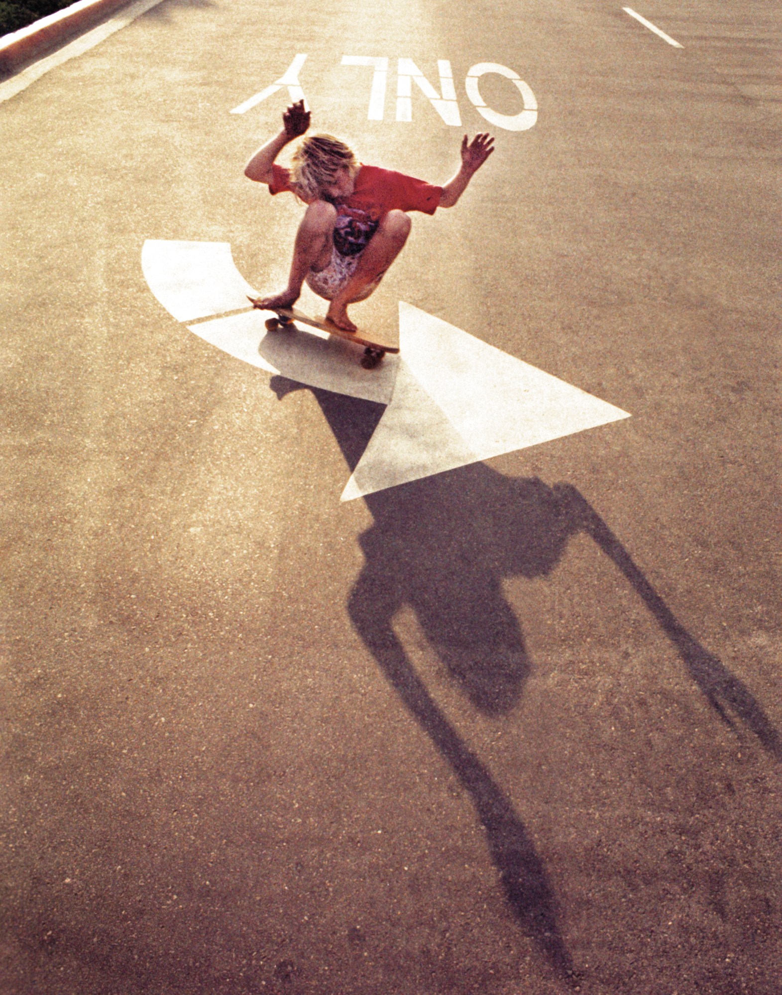 a kid with long hair skateboarding with his hands up in hollywood