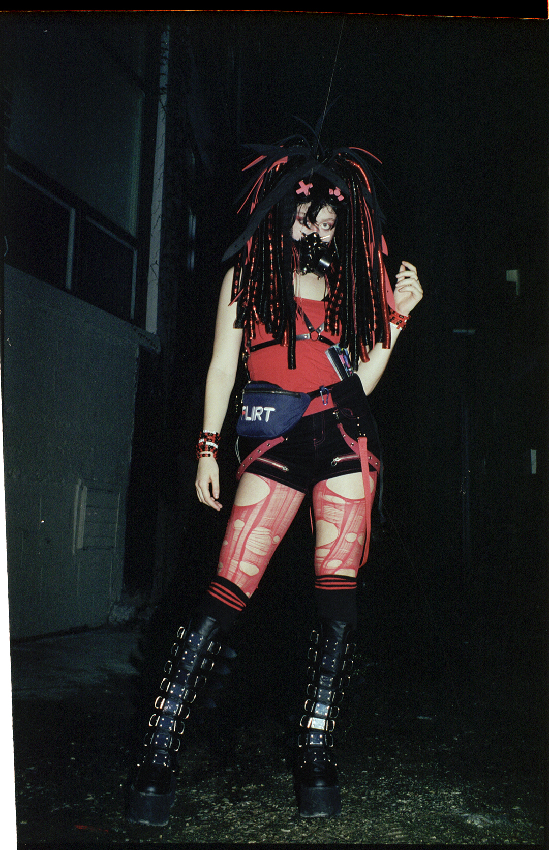 a cyber goth raver in a mask, braids and ripped tights in toronto