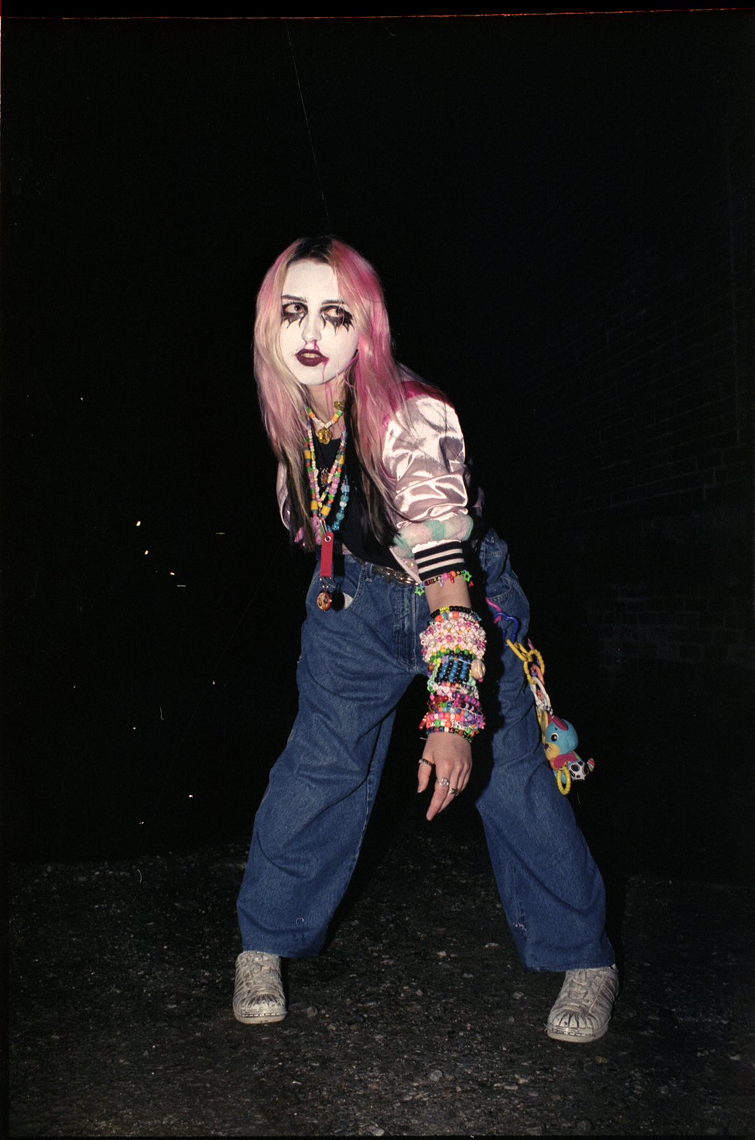 a girl with pink hair and white face makeup posing outside a rave in toronto