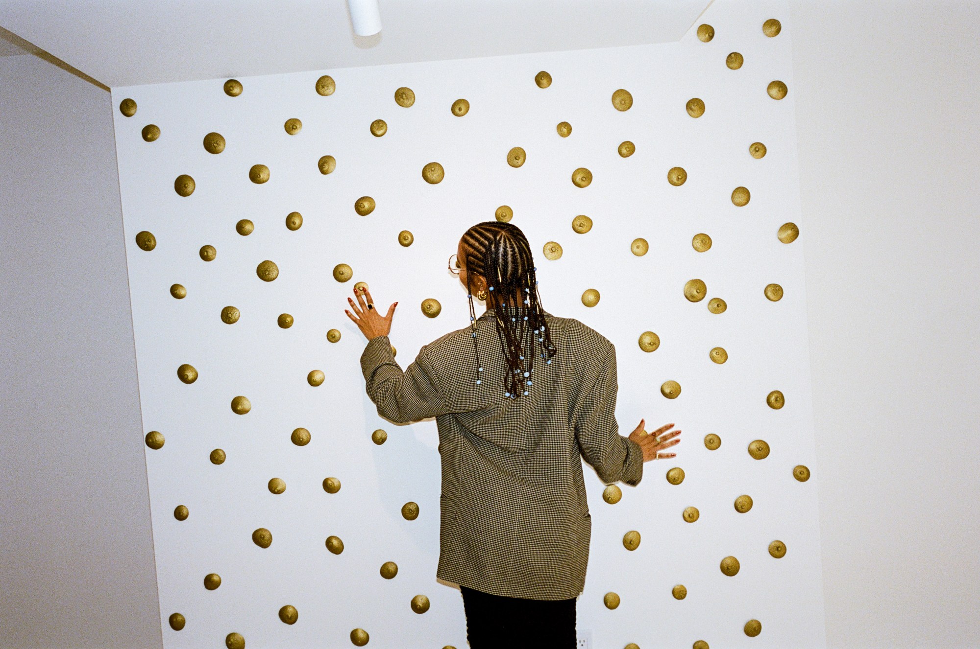 hannah traore touching gold objects on a wall in her gallery