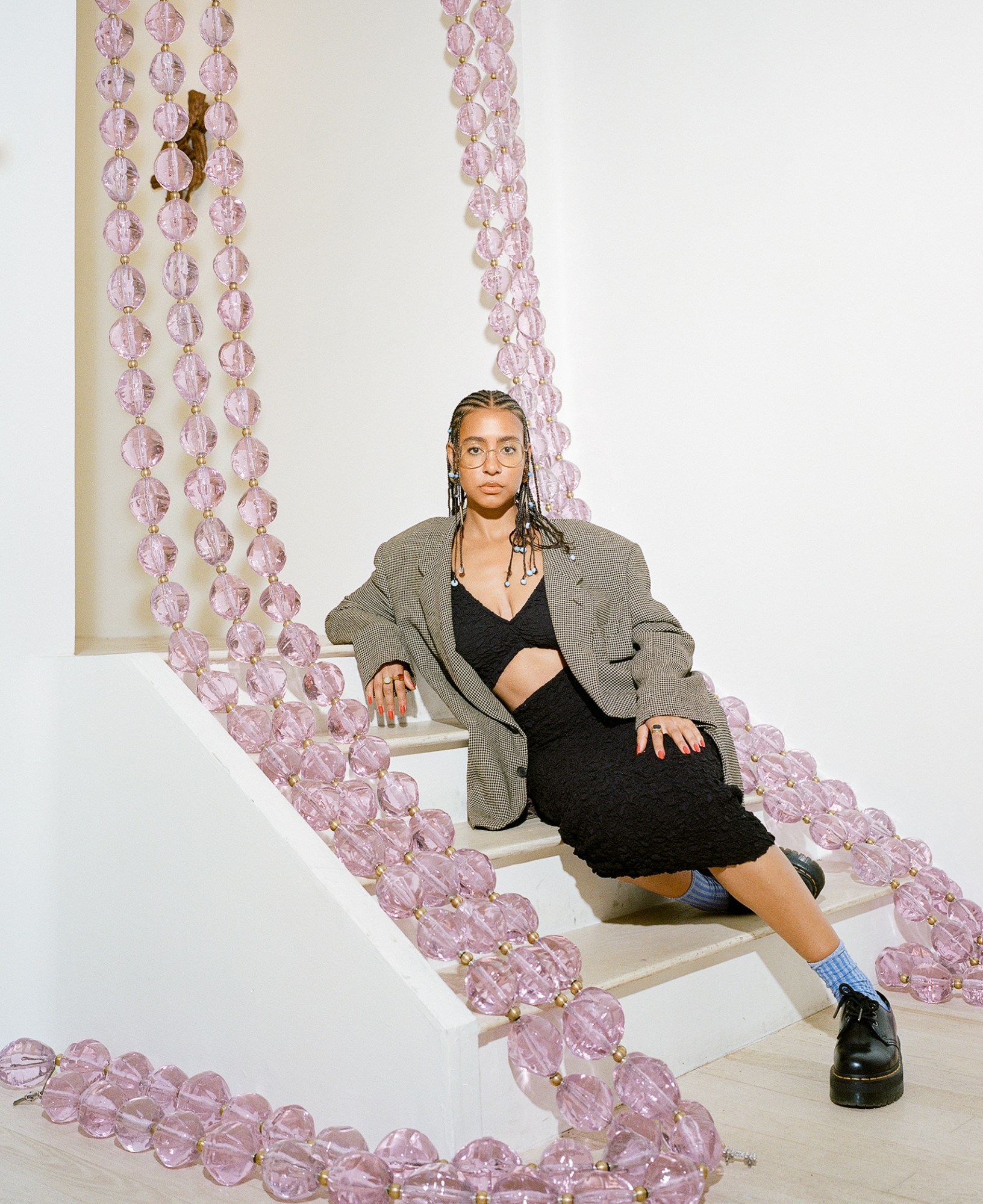 hannah traore sitting on stairs draped with large pink glass beads