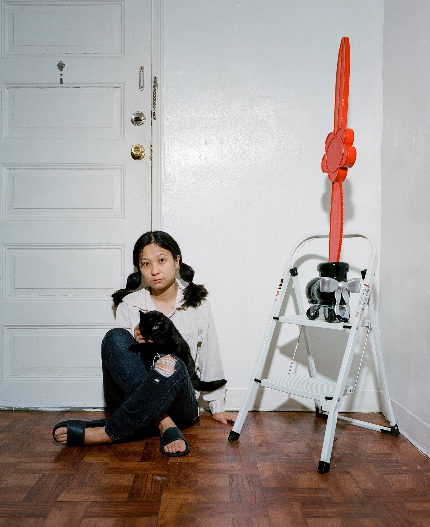 april zhu with her cat tutu sitting next to a red and black sculpture