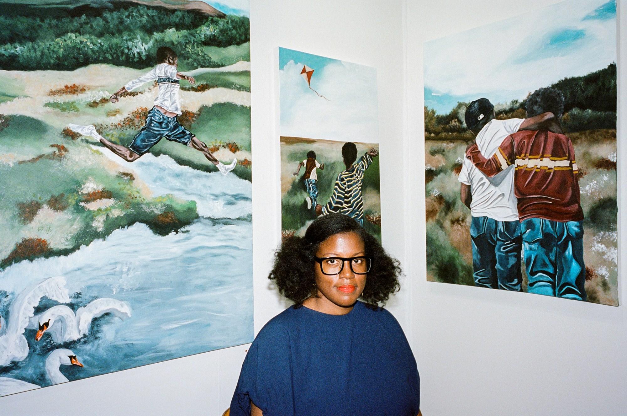 stephanie baptist standing in front of a selection of paintings at an art fair