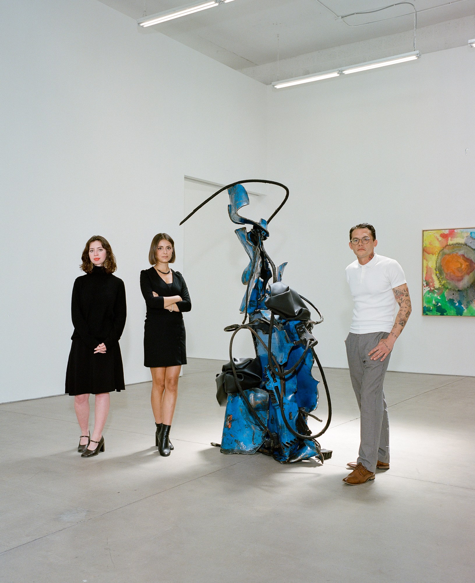 swivel gallery owners standing next to a blue and black sculpture