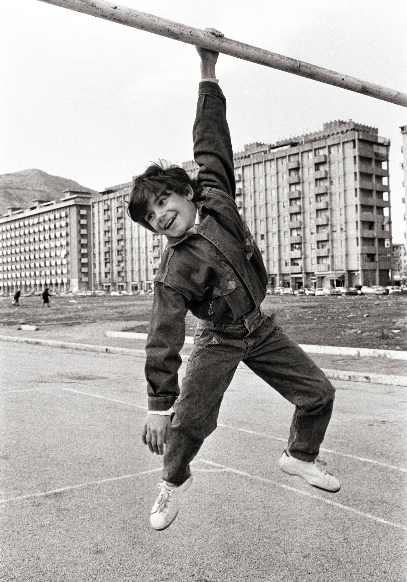 black-and-white photograph by Lia Pasqualino of a boy hanging from a goal post.