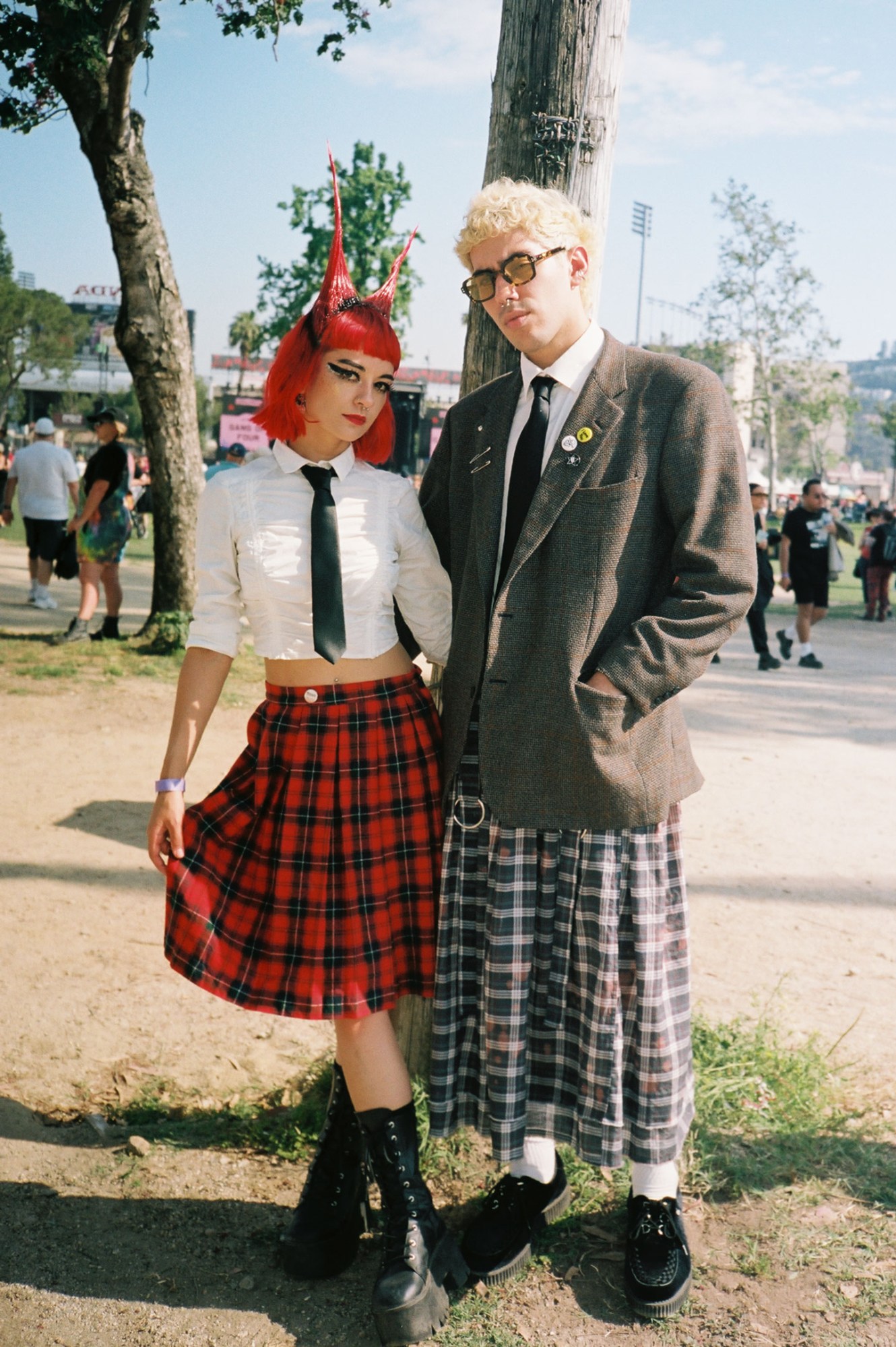 a punky goth couple wearing kilts and docs pose together; one of them has spiky bright red hair