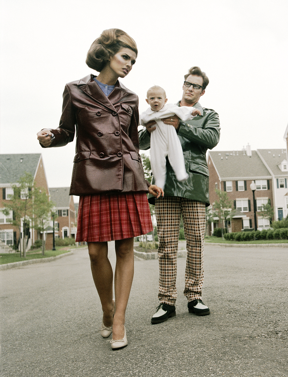 a staged suburban couple with a baby phtoographed in a driveway for guzman's the suburbanites