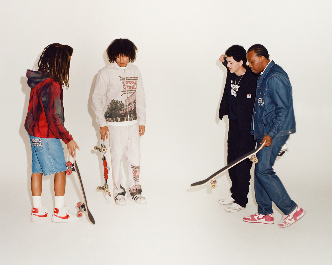 four models with skateboards stand in a white studio