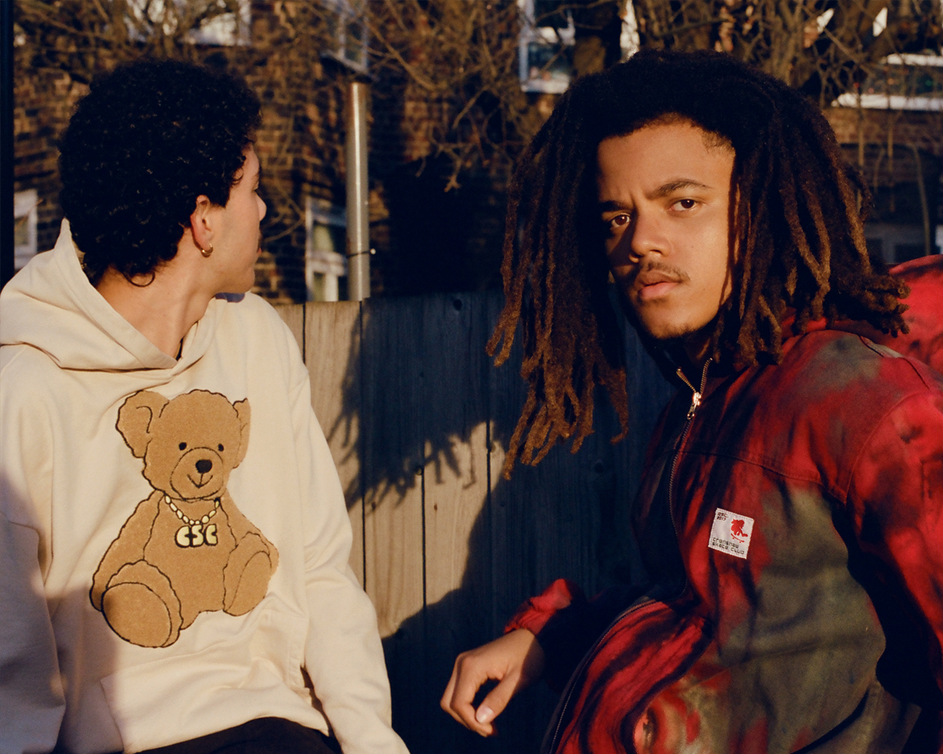 two skaters in hoodies sit in the sun in london