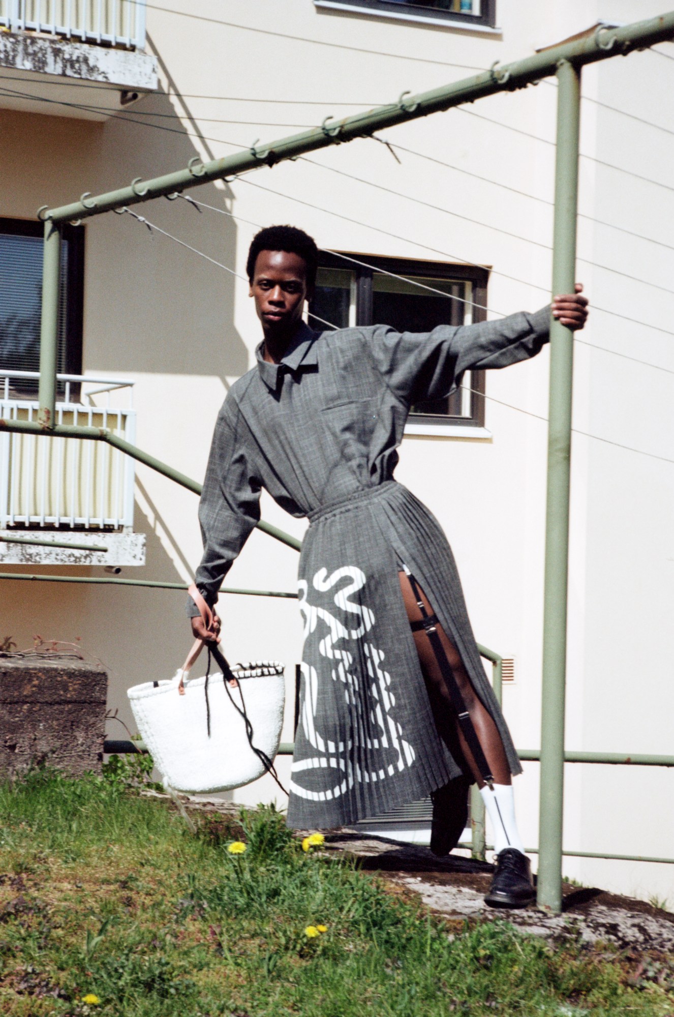 a model wearing latimmier in a park hanging off a green pole