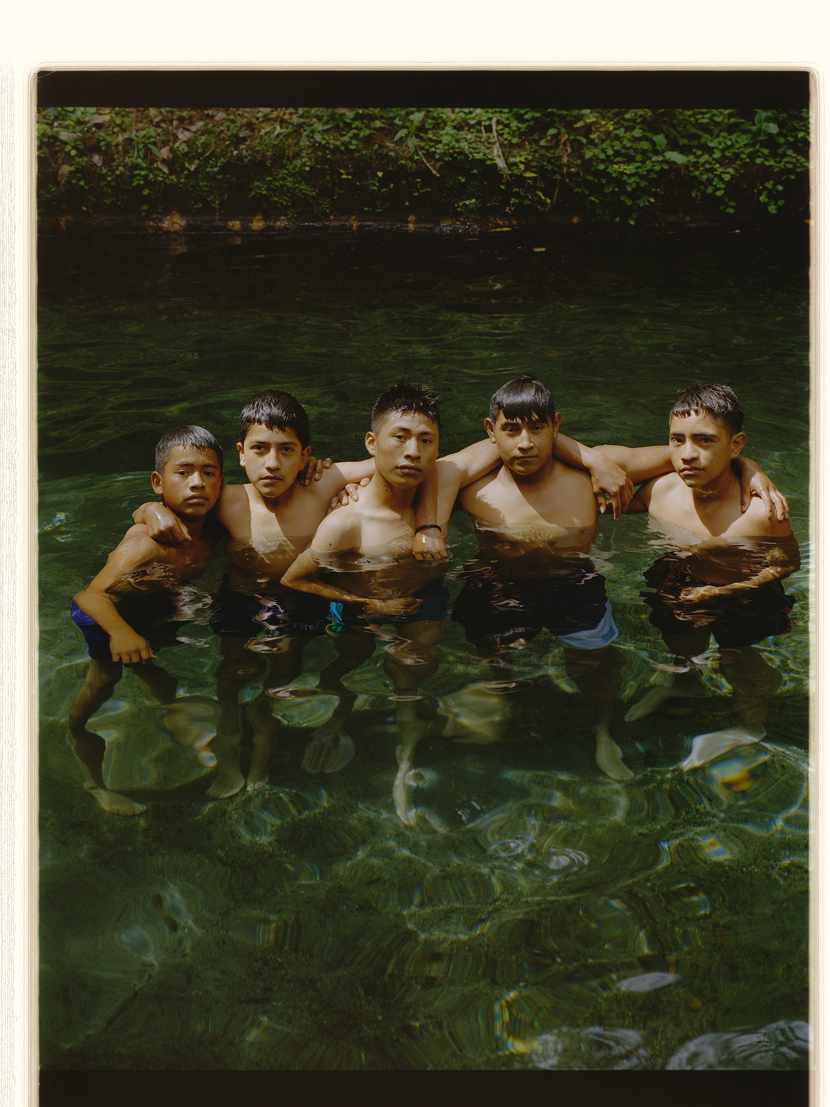 a photo of five guatemalan boys posing together in the water