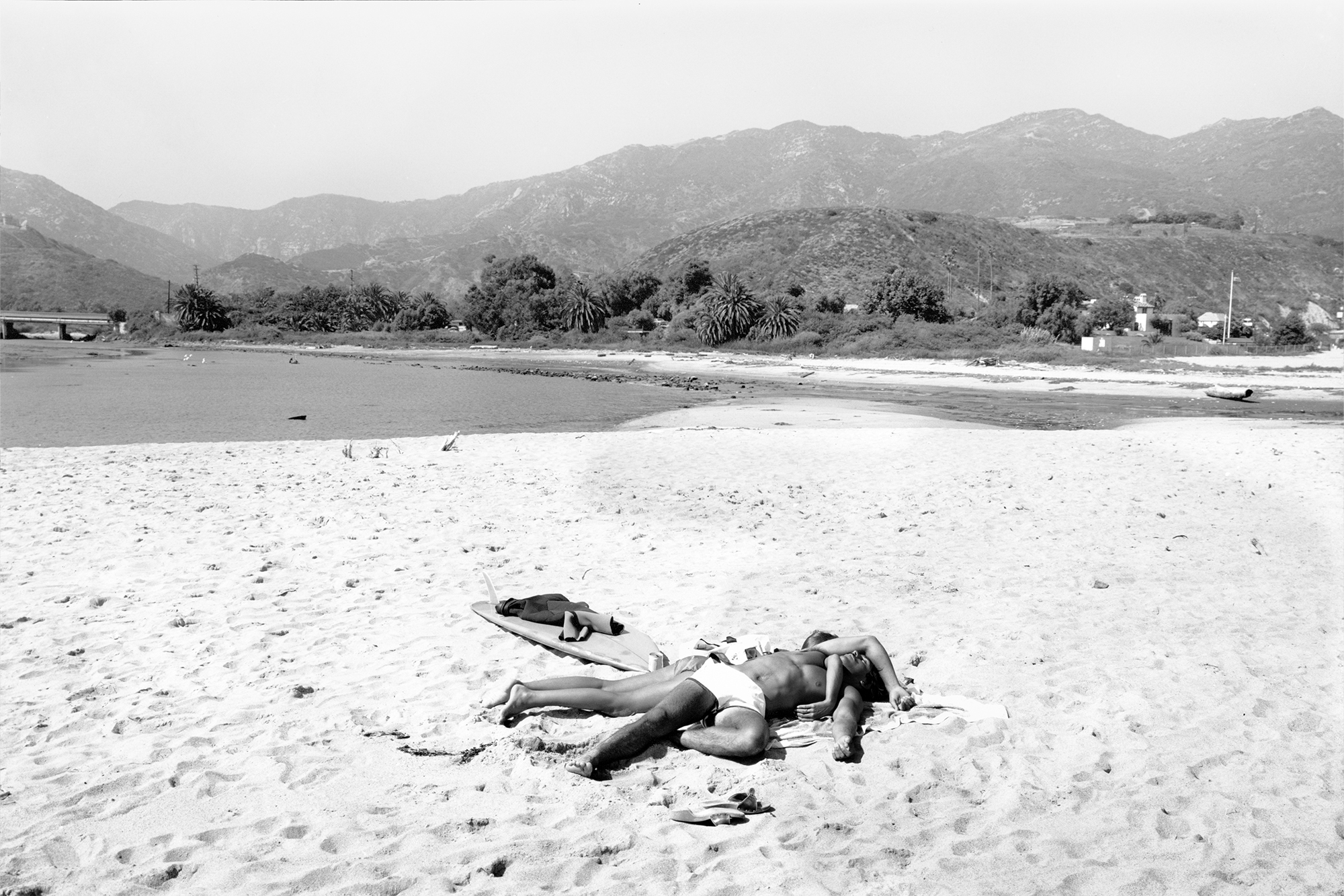 black-and-white picture of a couple sleeping on a beach