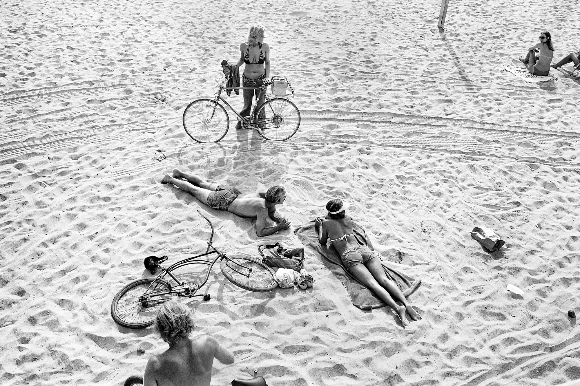 black-and-white image of teenagers with bicycles posing on the beach