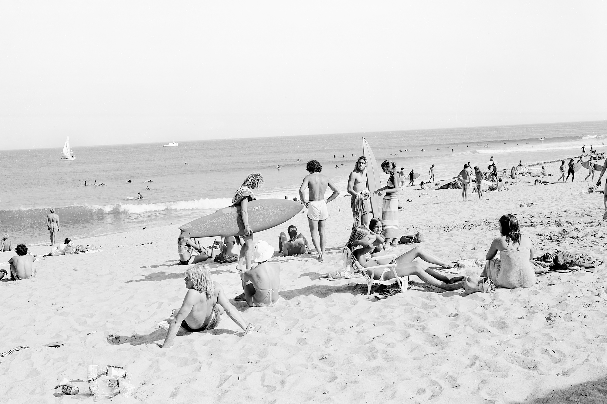 black-and-white image of teenagers with surfboards hanging out on the beach