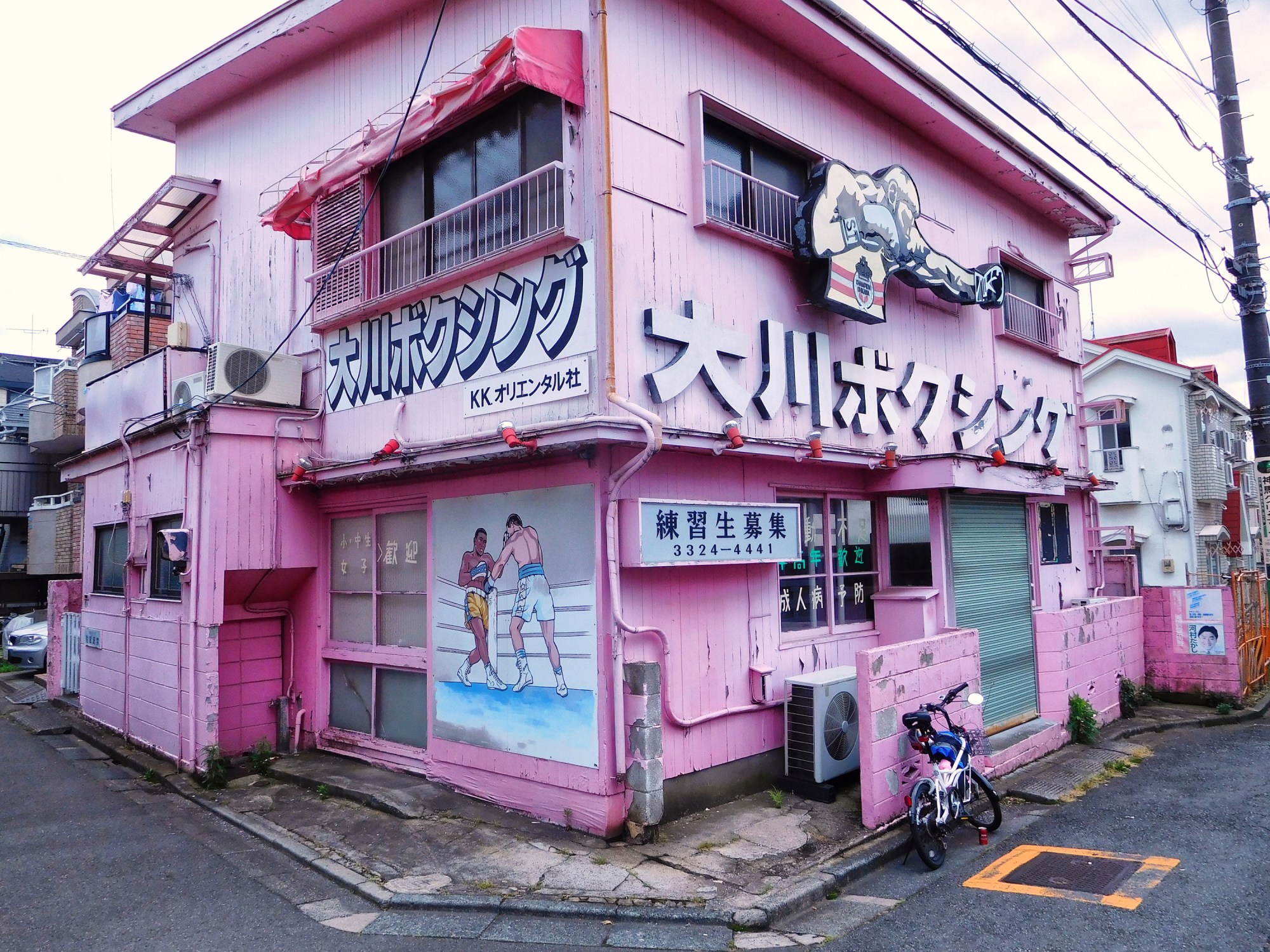 a pink building in tokyo with japanese text and boxers on it.