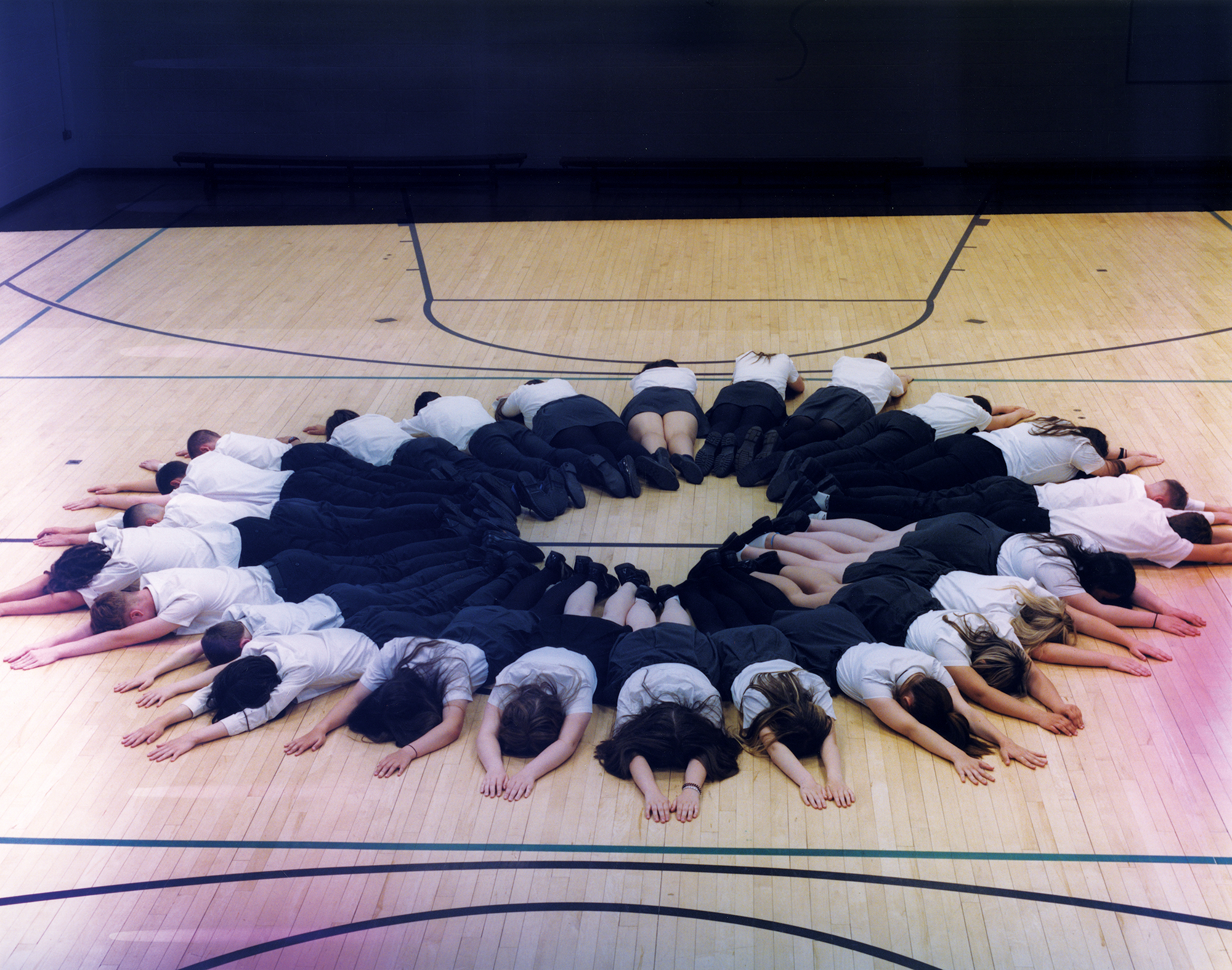 a photograph of a group of school girls lying face down in a circle