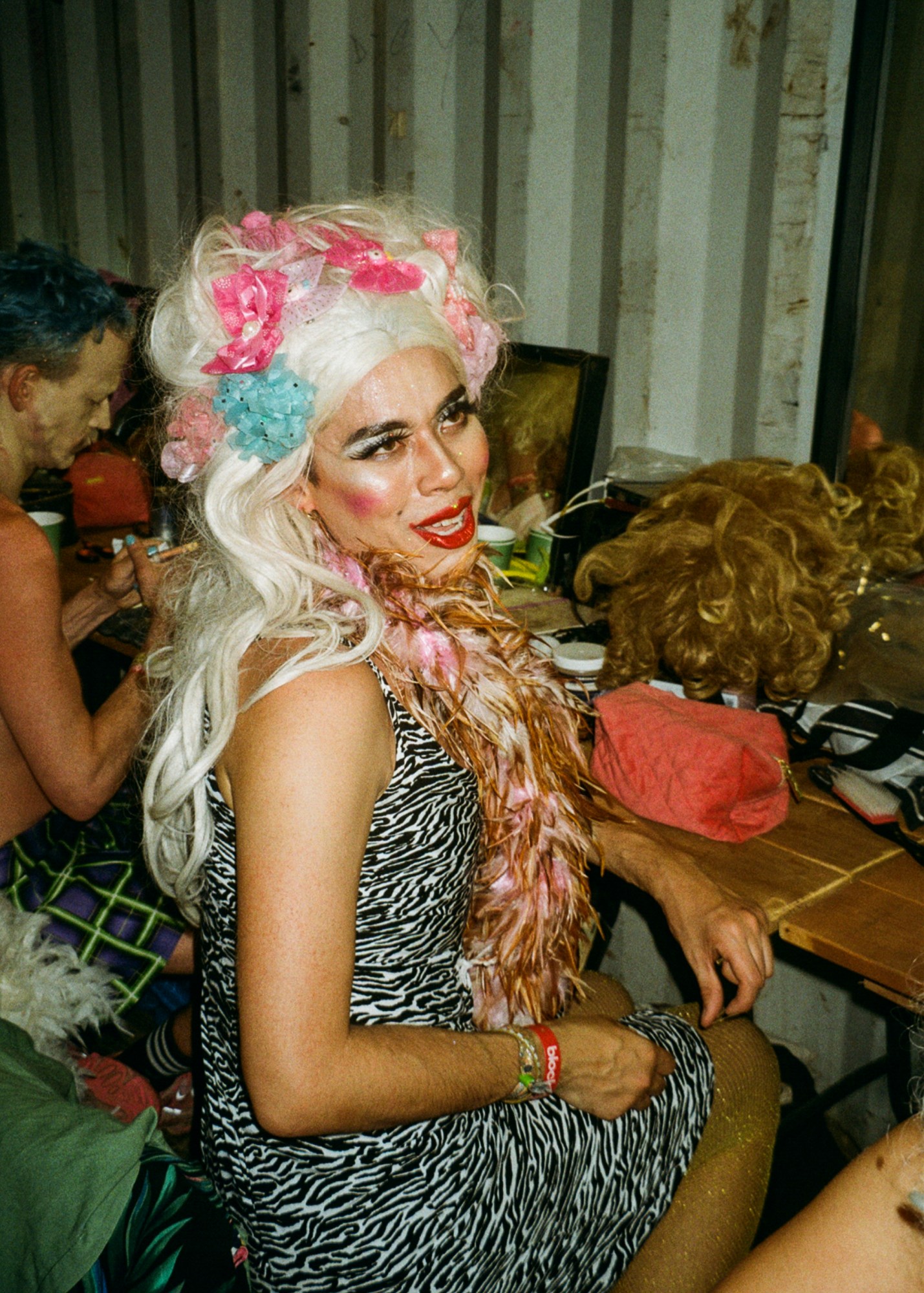 a club goer in a blonde wig and zebra printed dress with a pink and brown boa