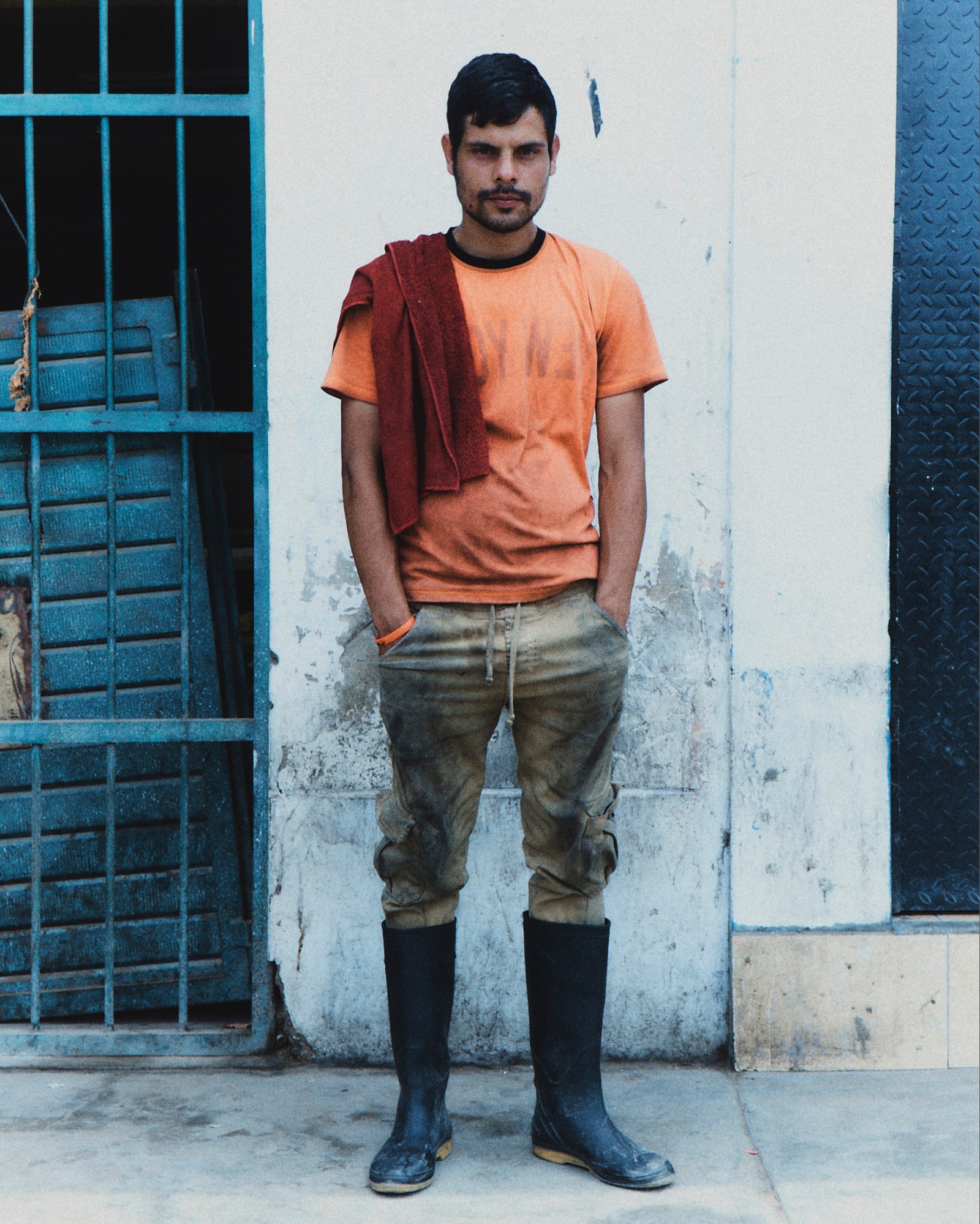 a car wash worked in dirty clothes and boots posing with his hands in his pockets