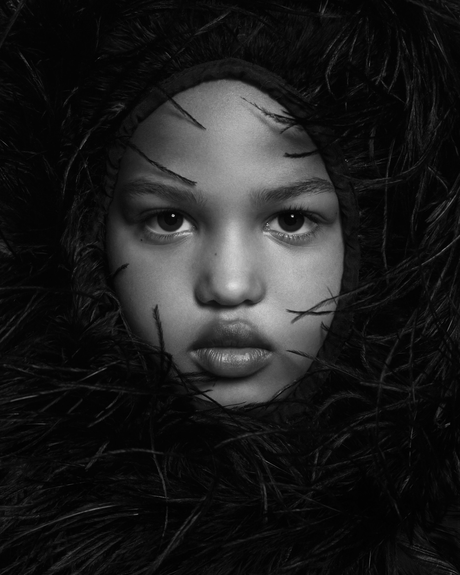 a kid's face surrounded by a large black feathered item of clothing