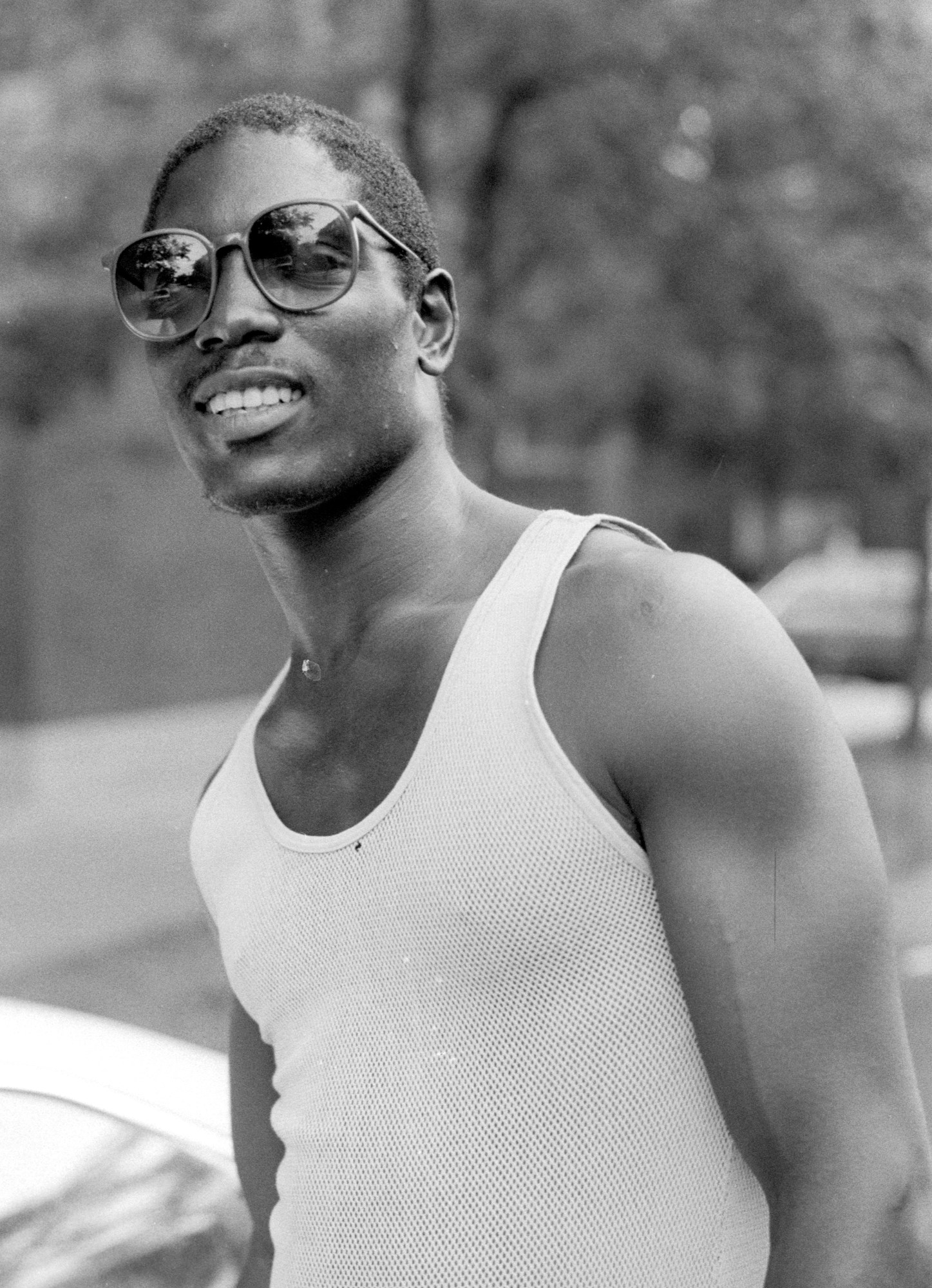 a man in black sunglasses and a white tank top