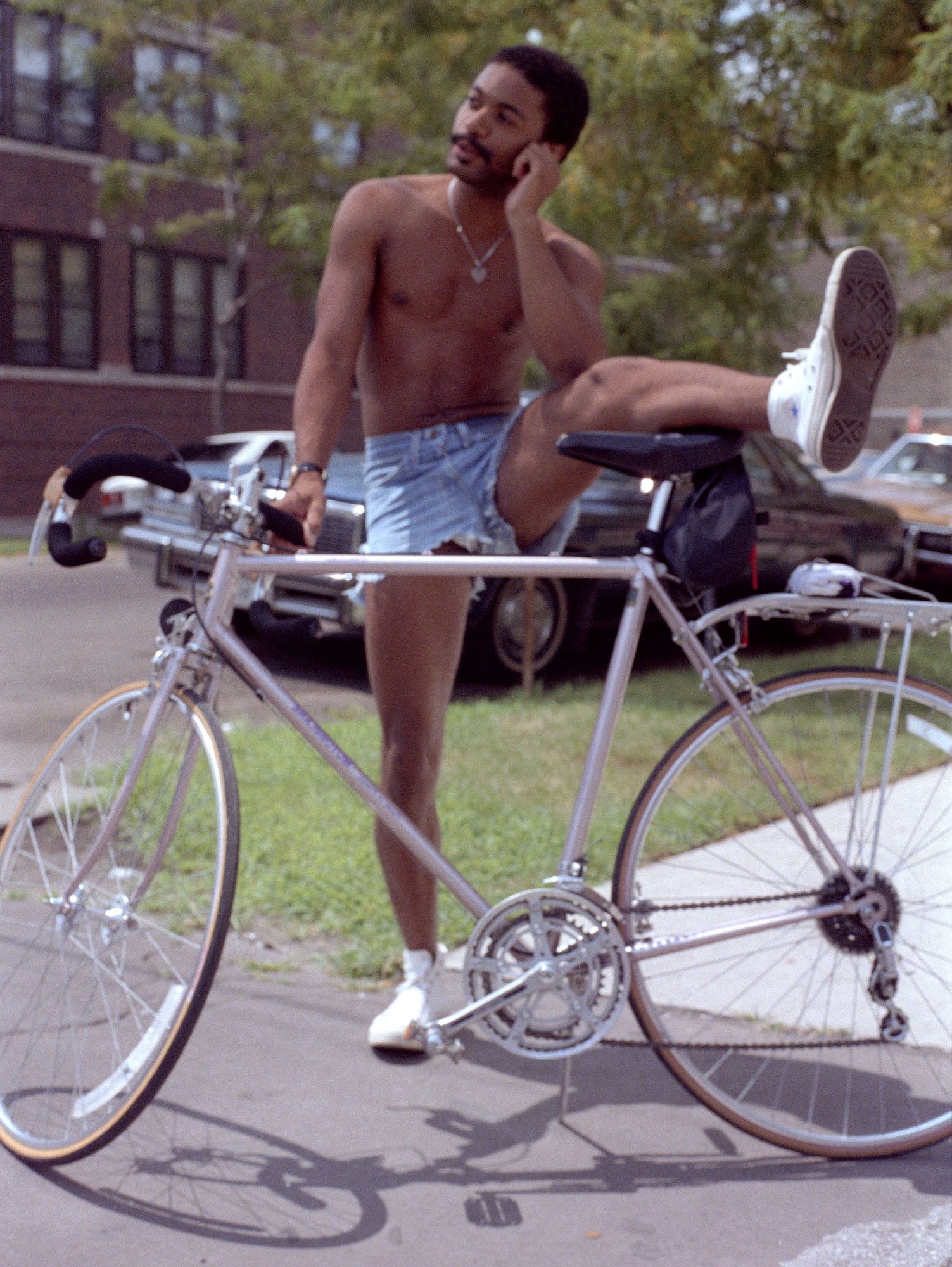 a man standing next to his bike wearing short jean shorts