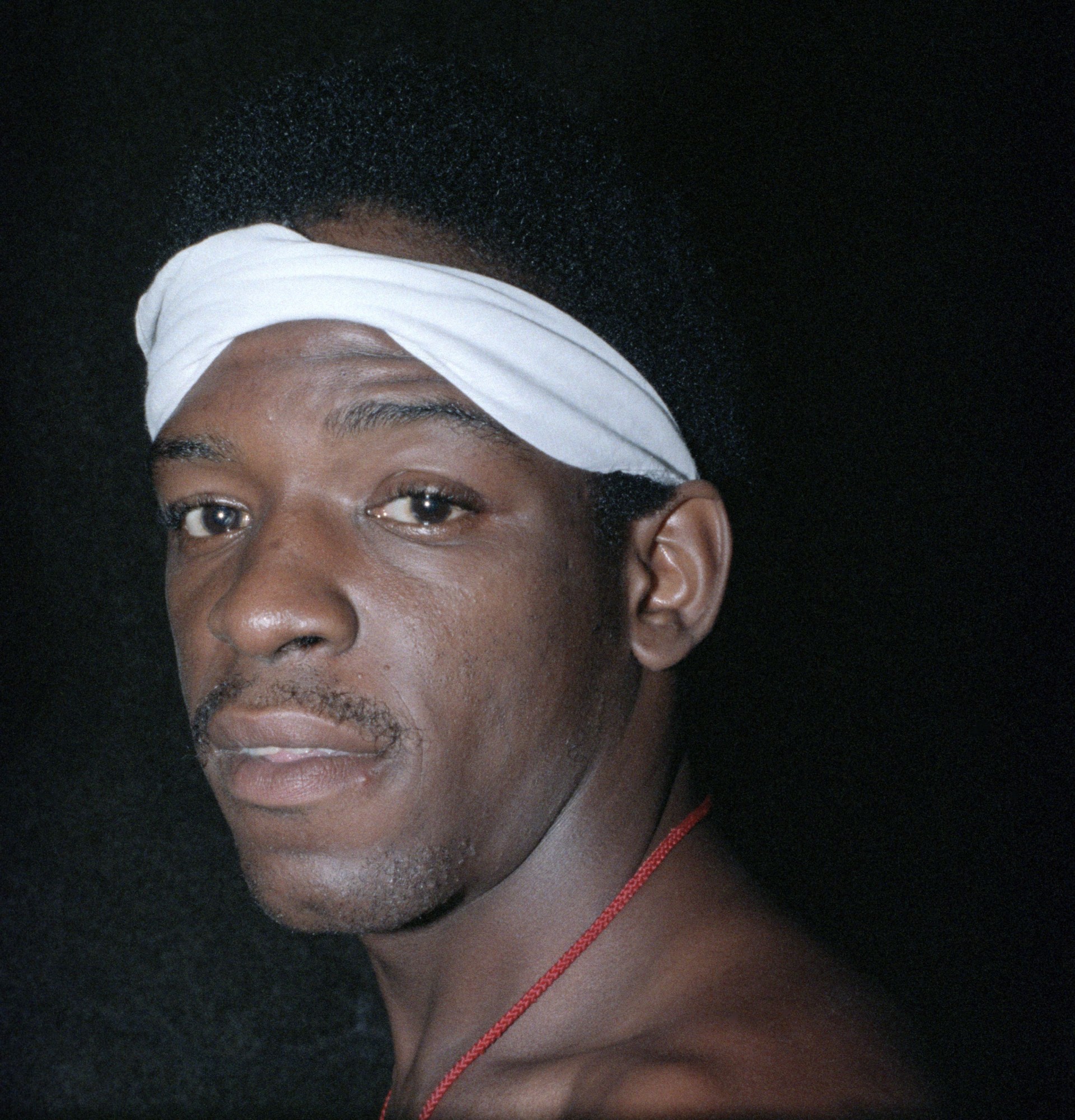 a man wearing a white headband looking into the camera