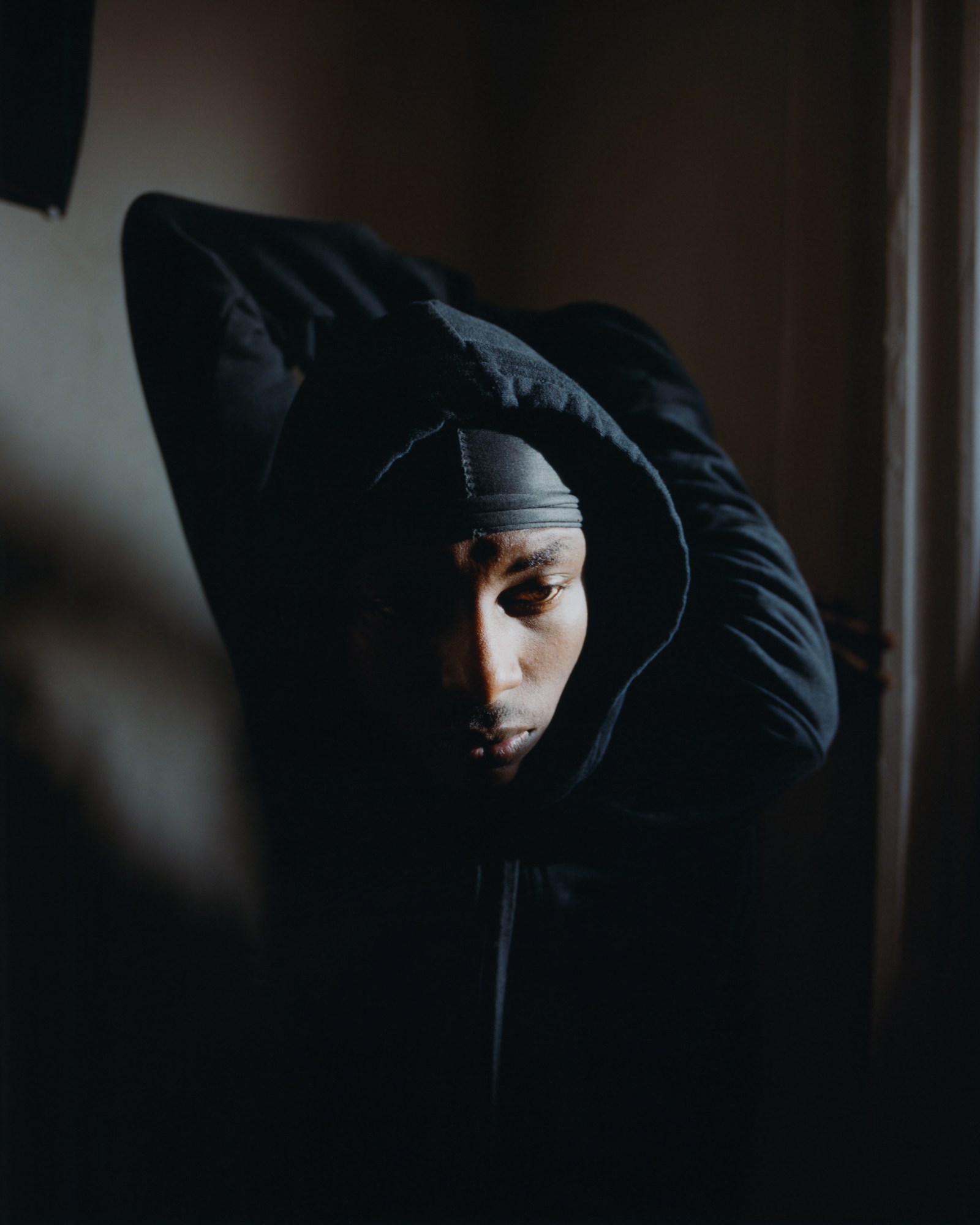 a dancer named vaughn in a black hoodie photographed in his home in dc