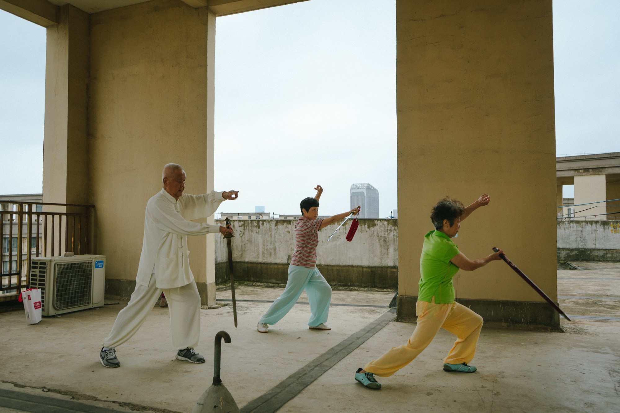 three people practicing tai chi on a rooftop