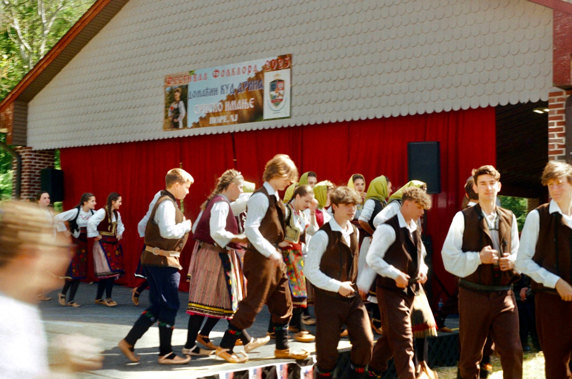 a crowd of teenagers in traditional serbian clothing at a festival