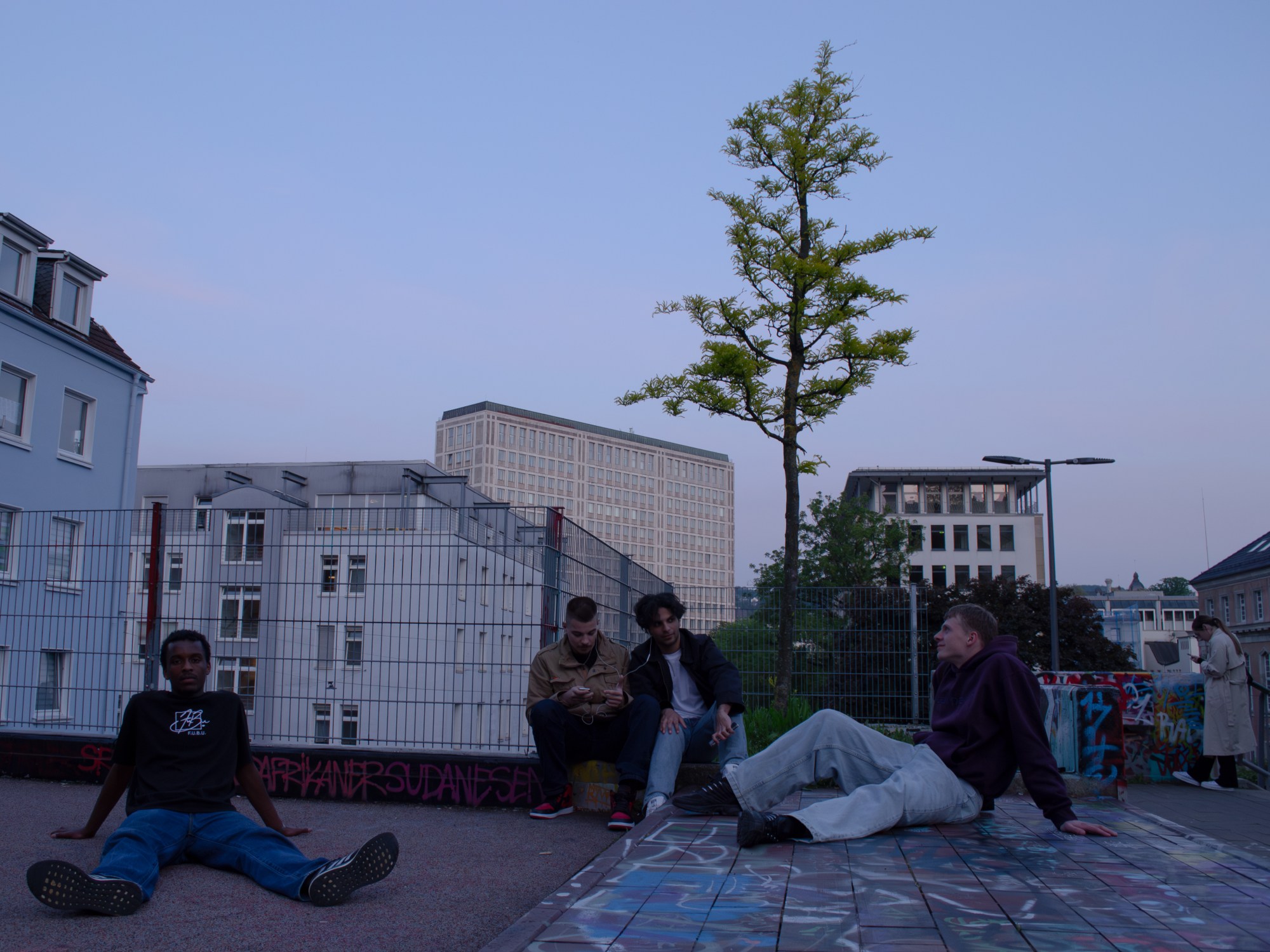 four teenagers hanging out in a city at dusk