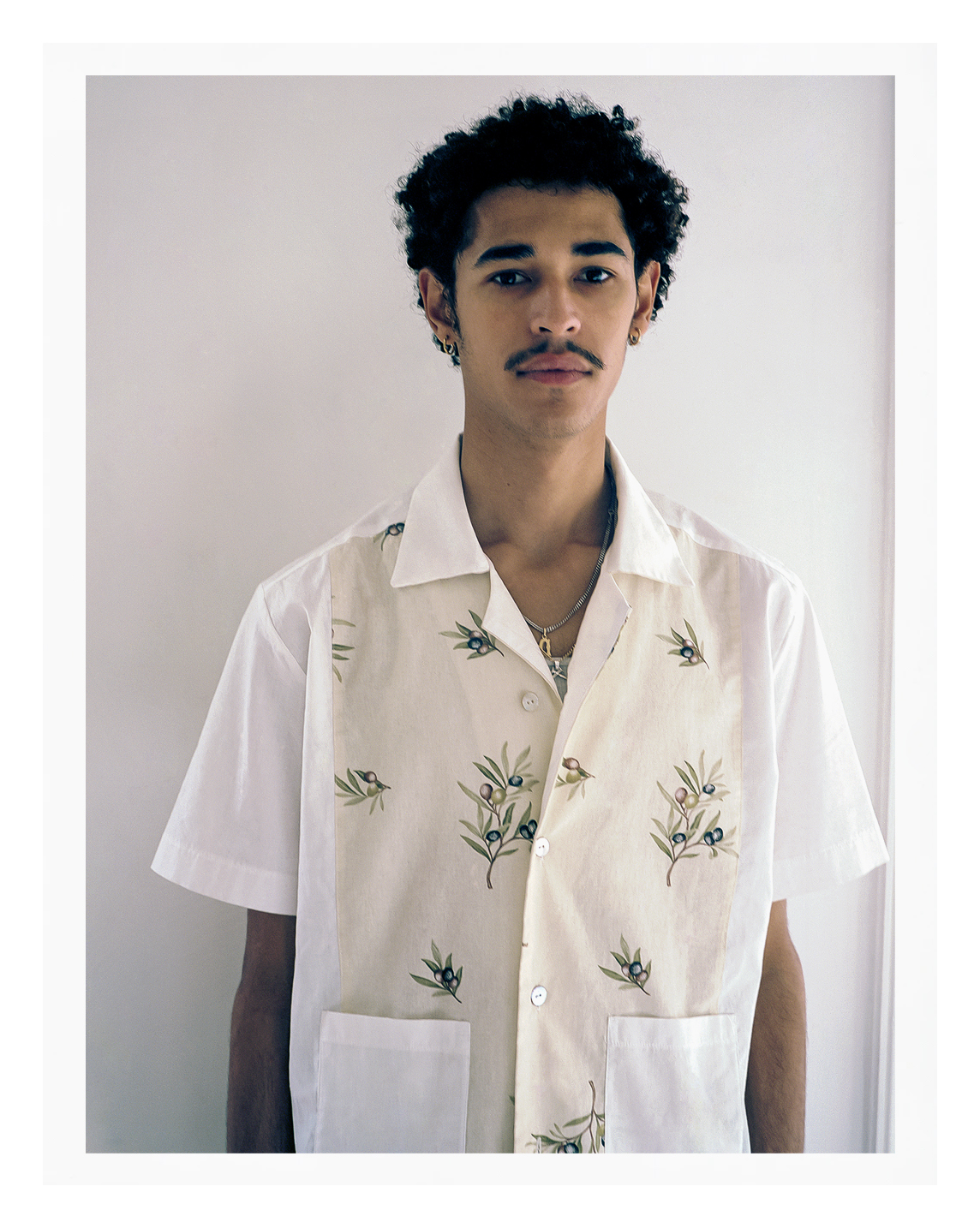 a black Parisian young person wearing a white shirt with olive branches on it