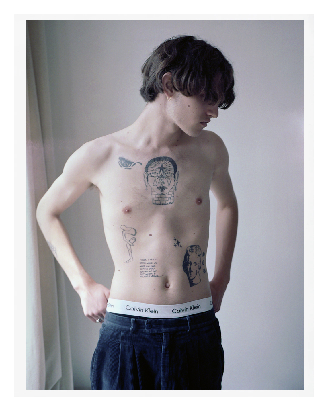 a white parisian teenager with graphic tattoos on their bare stomach. they have short brown hair.