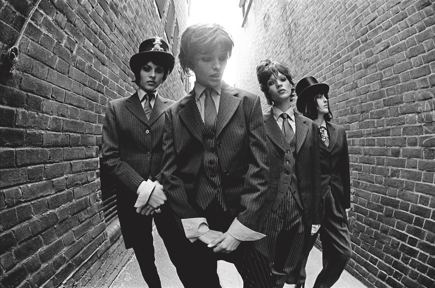 black-and-white image of four models in an alleywway dressed as victorian gentlemen