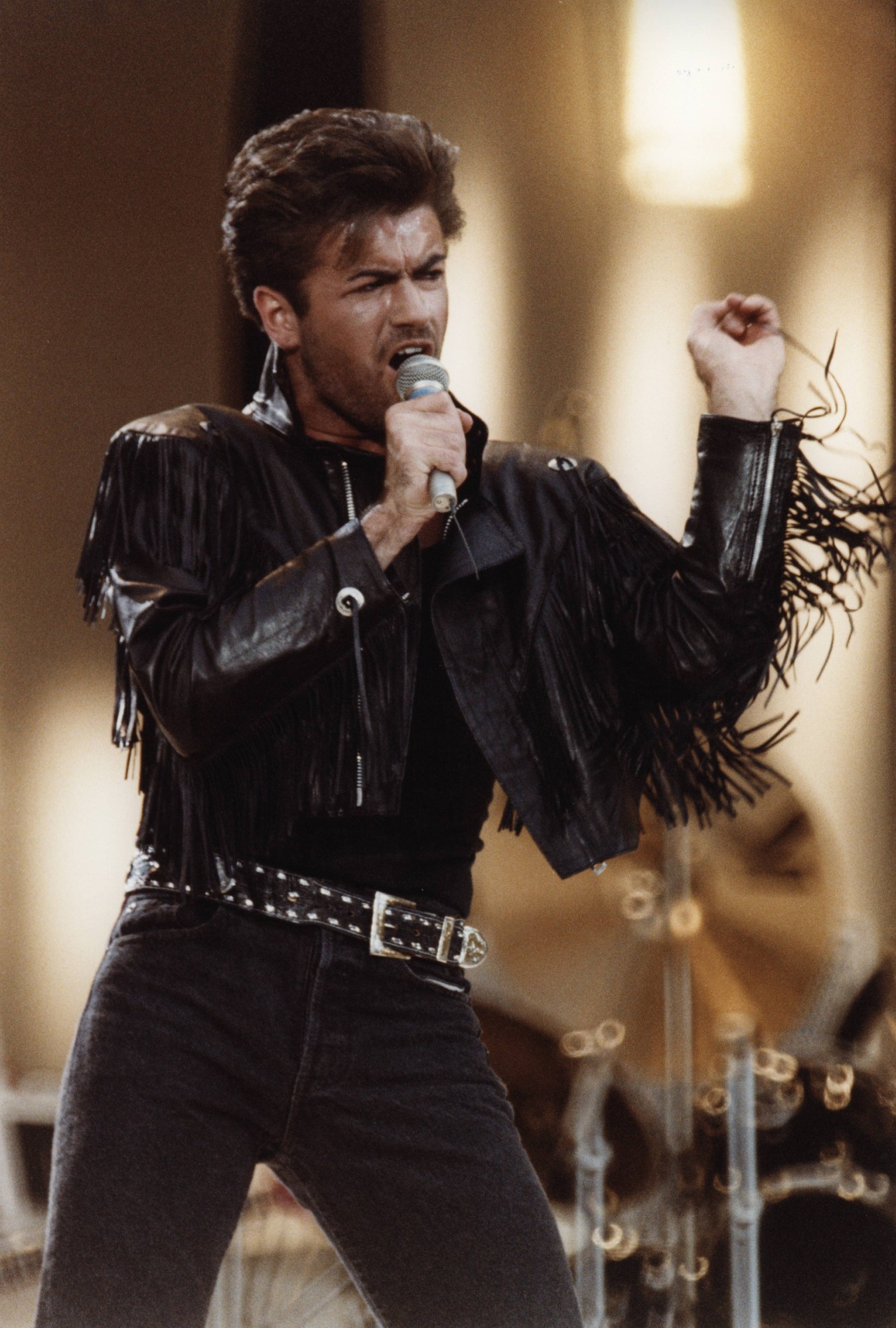 geoge michael on stage in a black fringe leather jacket