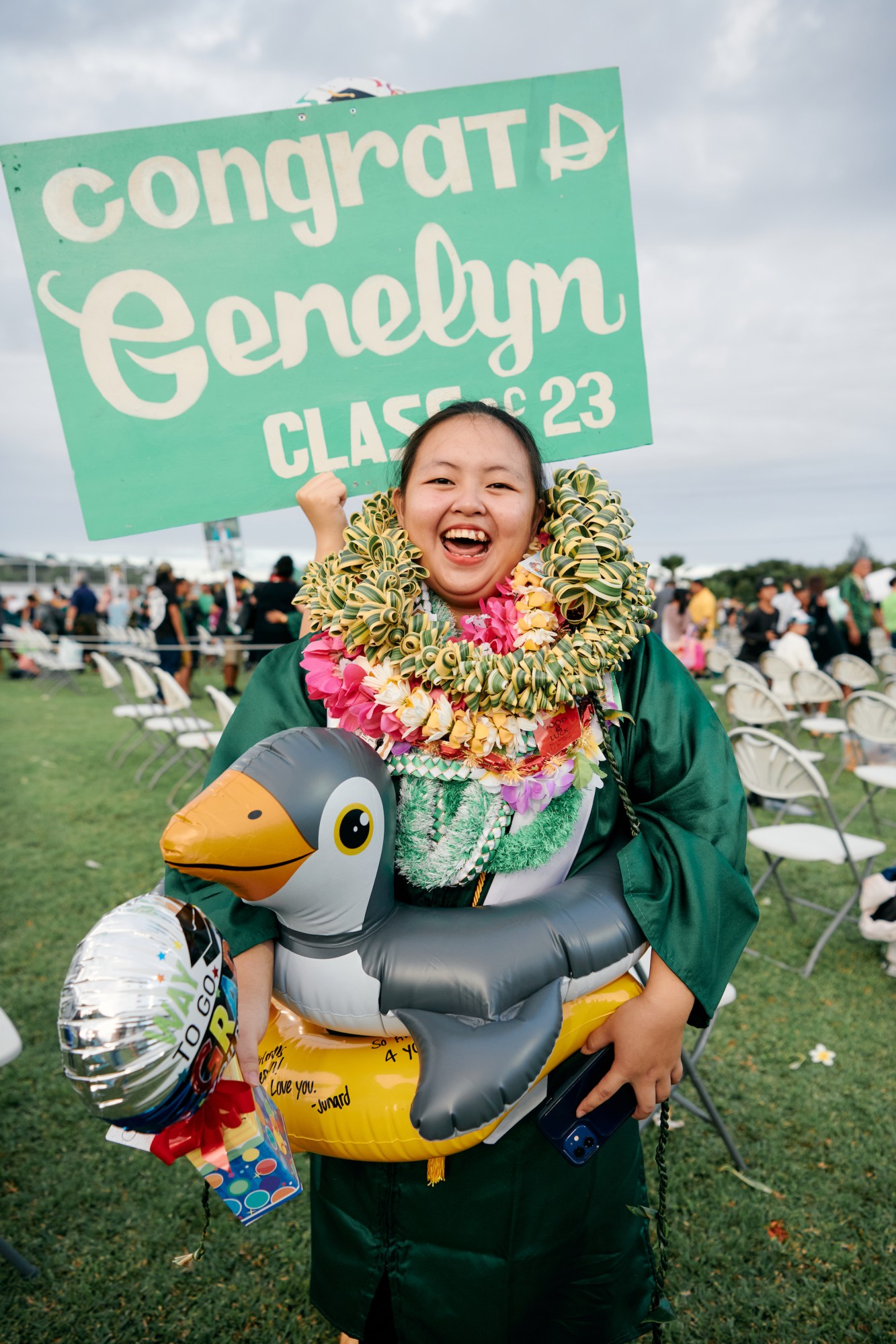 a student named genelyn posing with her graduation leis in the grass