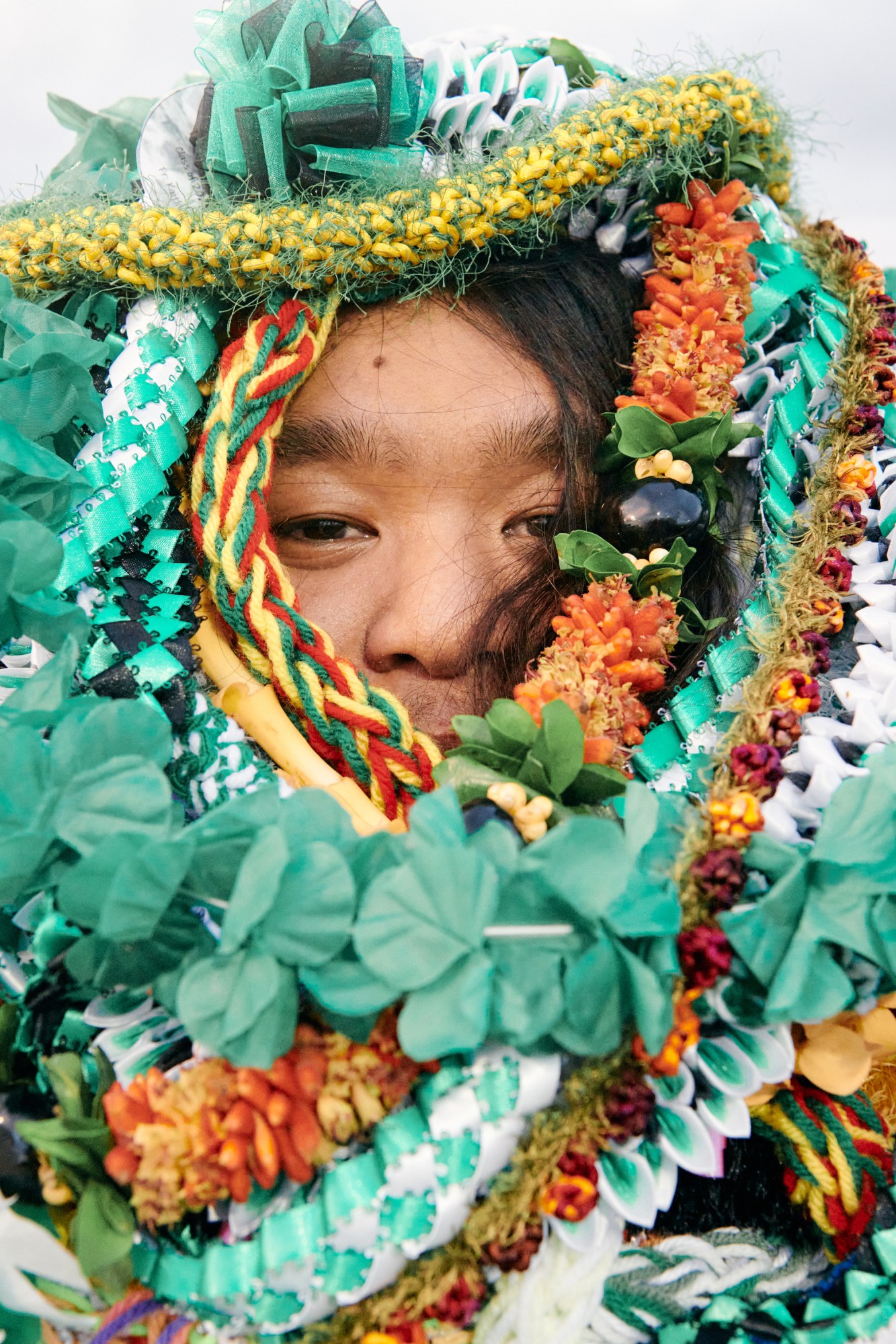 close up of a high school graduate covered in green, orange and yellow leis in hawaii