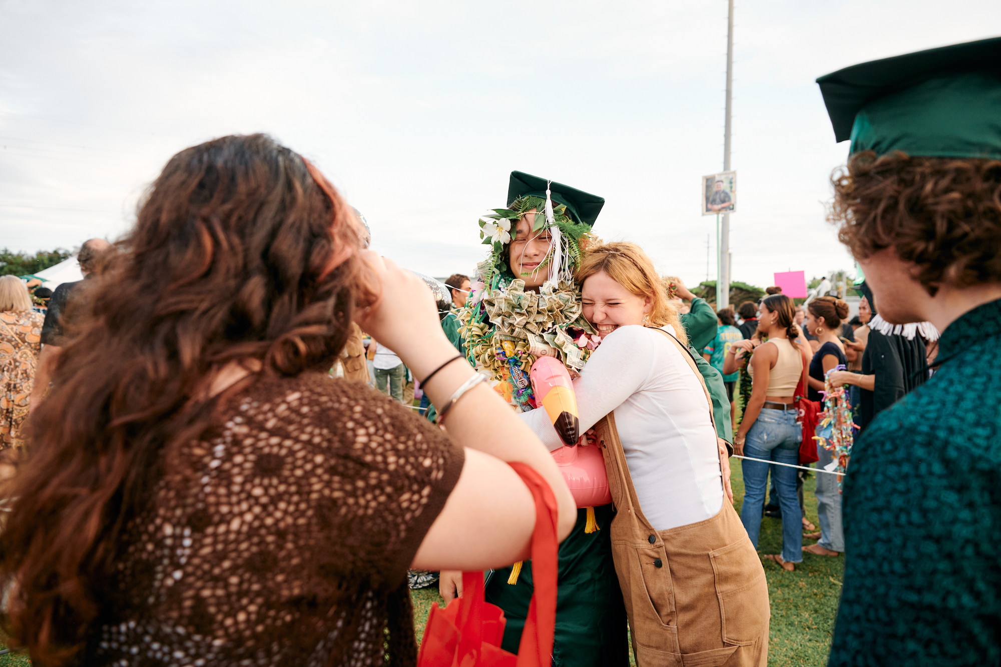 students hugging and taking pictures at a high school graduation in hawaii