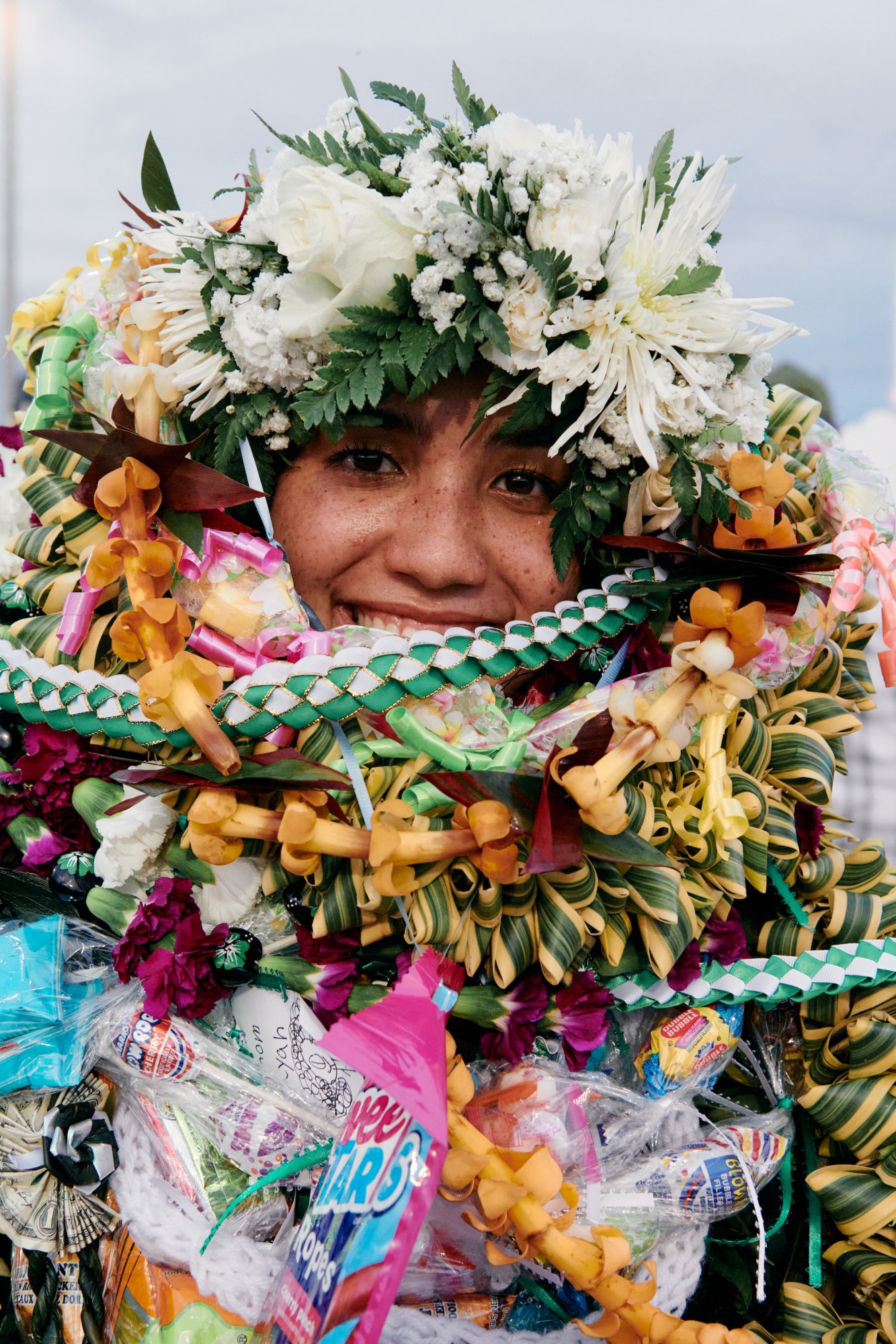 close up of a student covered in candy and floral hawaiian leis