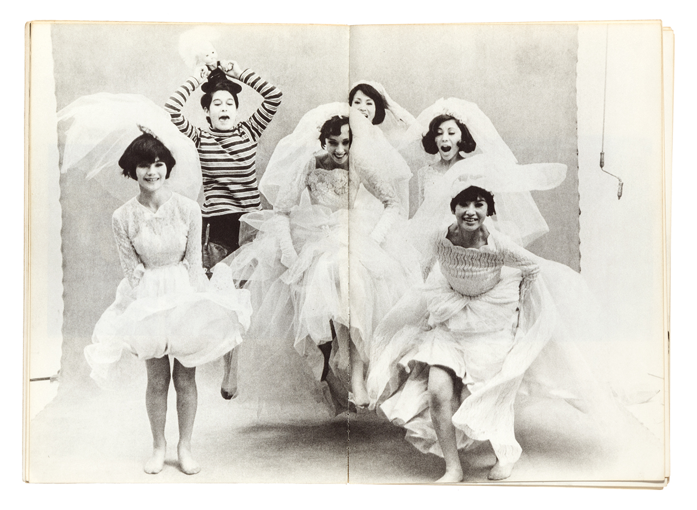 black-and-white image of young women in wedding dresses jumping in front of the camera