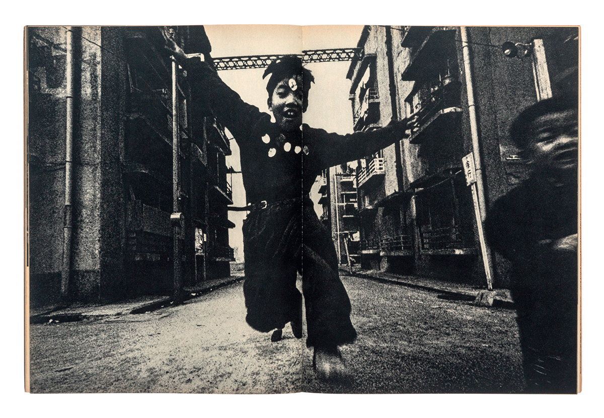 black-and-white image of a japanese boy running through the streets