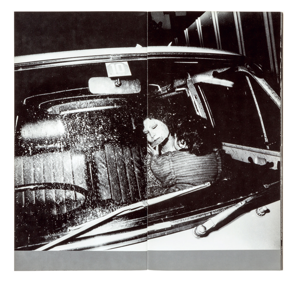 black-and-white image of a woman in a car at night with her baby on her lap facing away from the camera