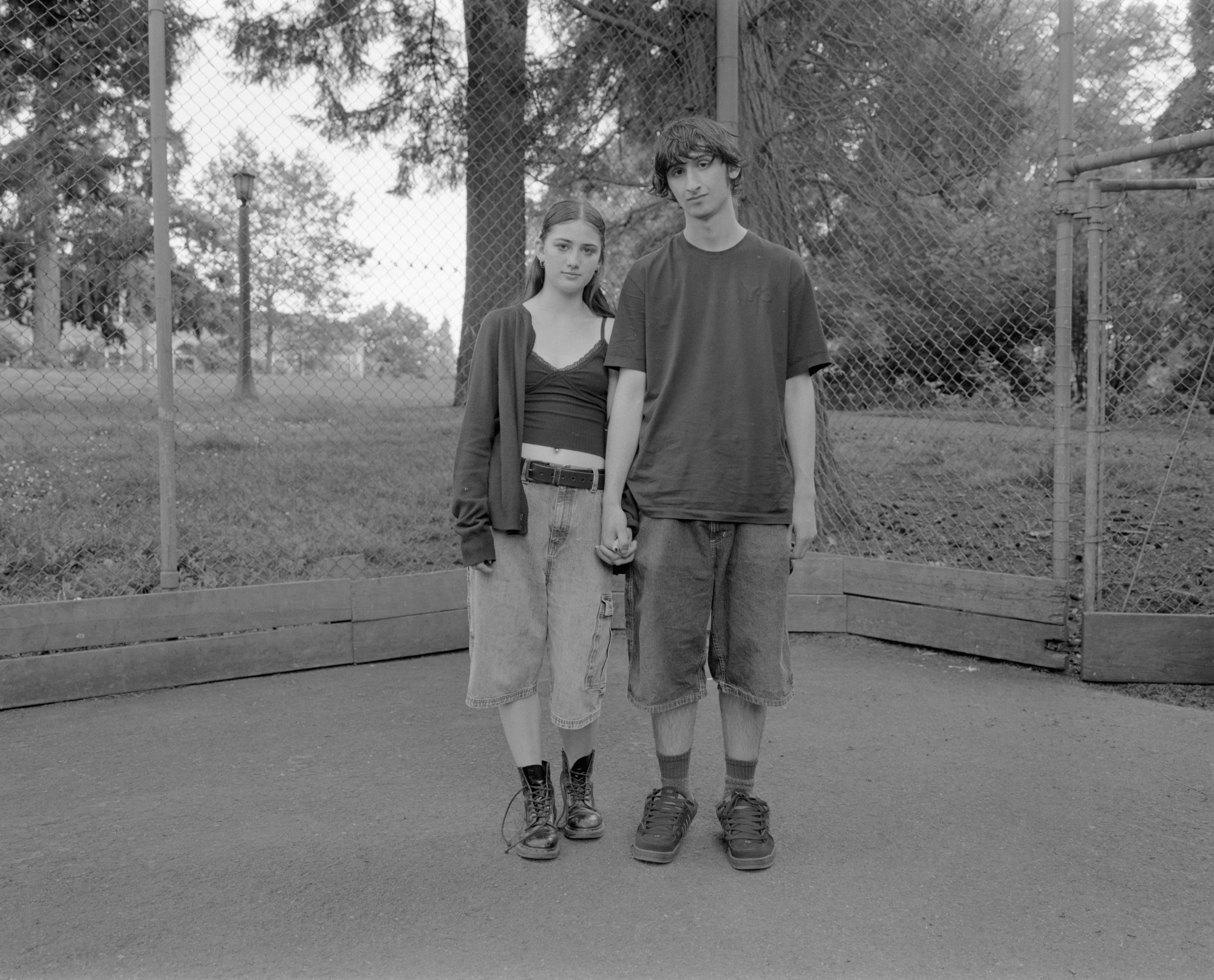 a young couple in baggy jean shorts and combats boots holding hands