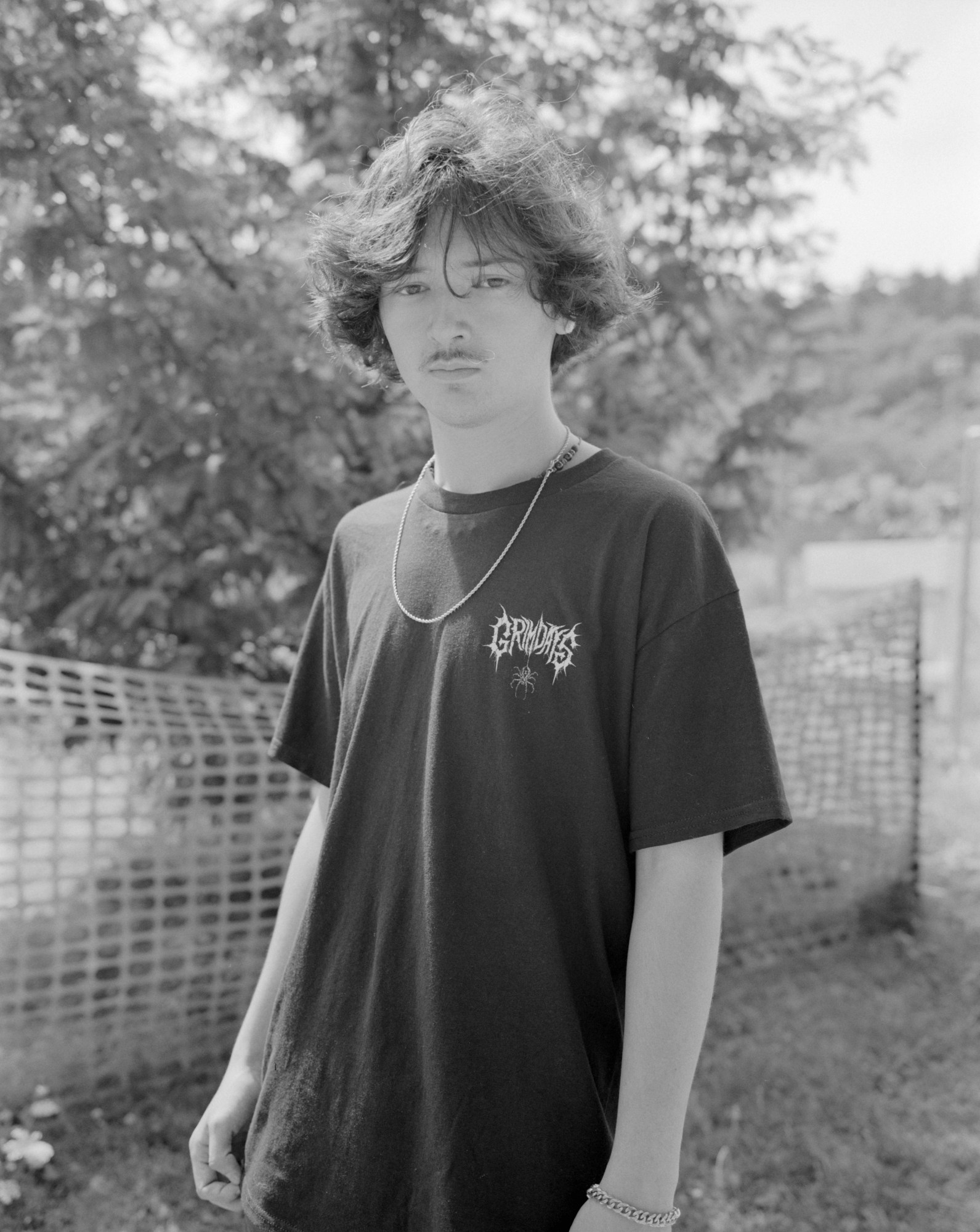 a young man with a mustache and chain necklace