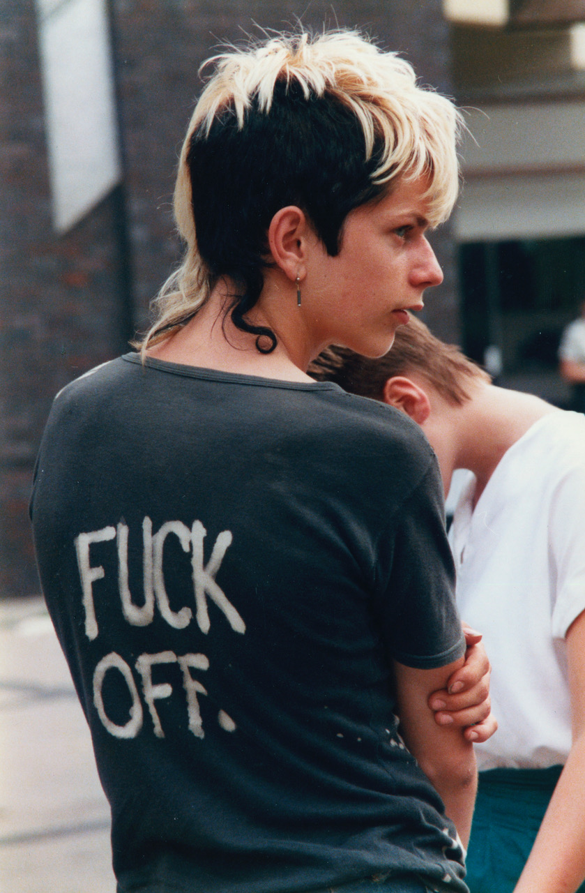 a young punk wearing a black t-shirt with the words fuck off written on the back