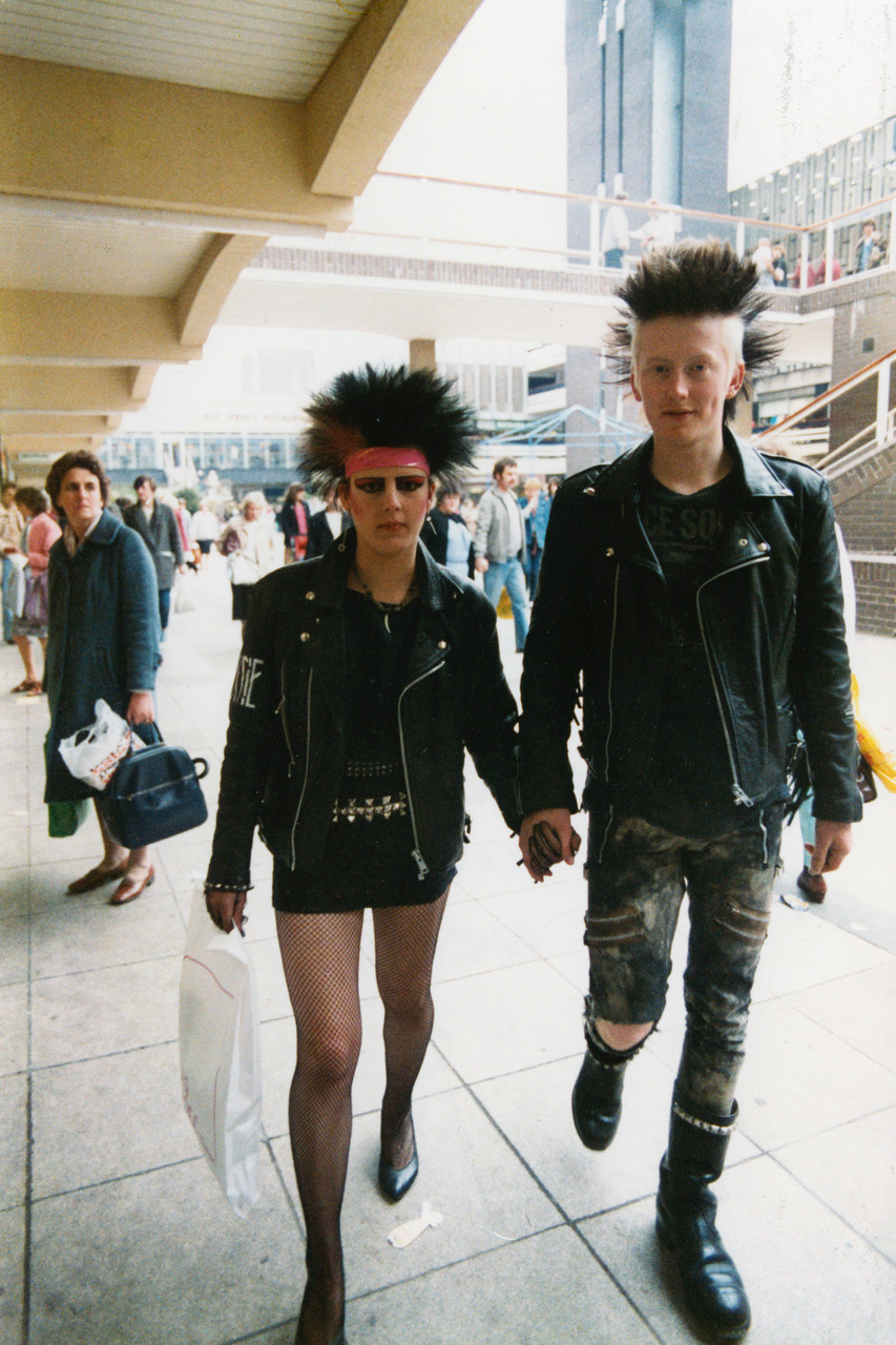 a young punk couple walk through a shopping mal