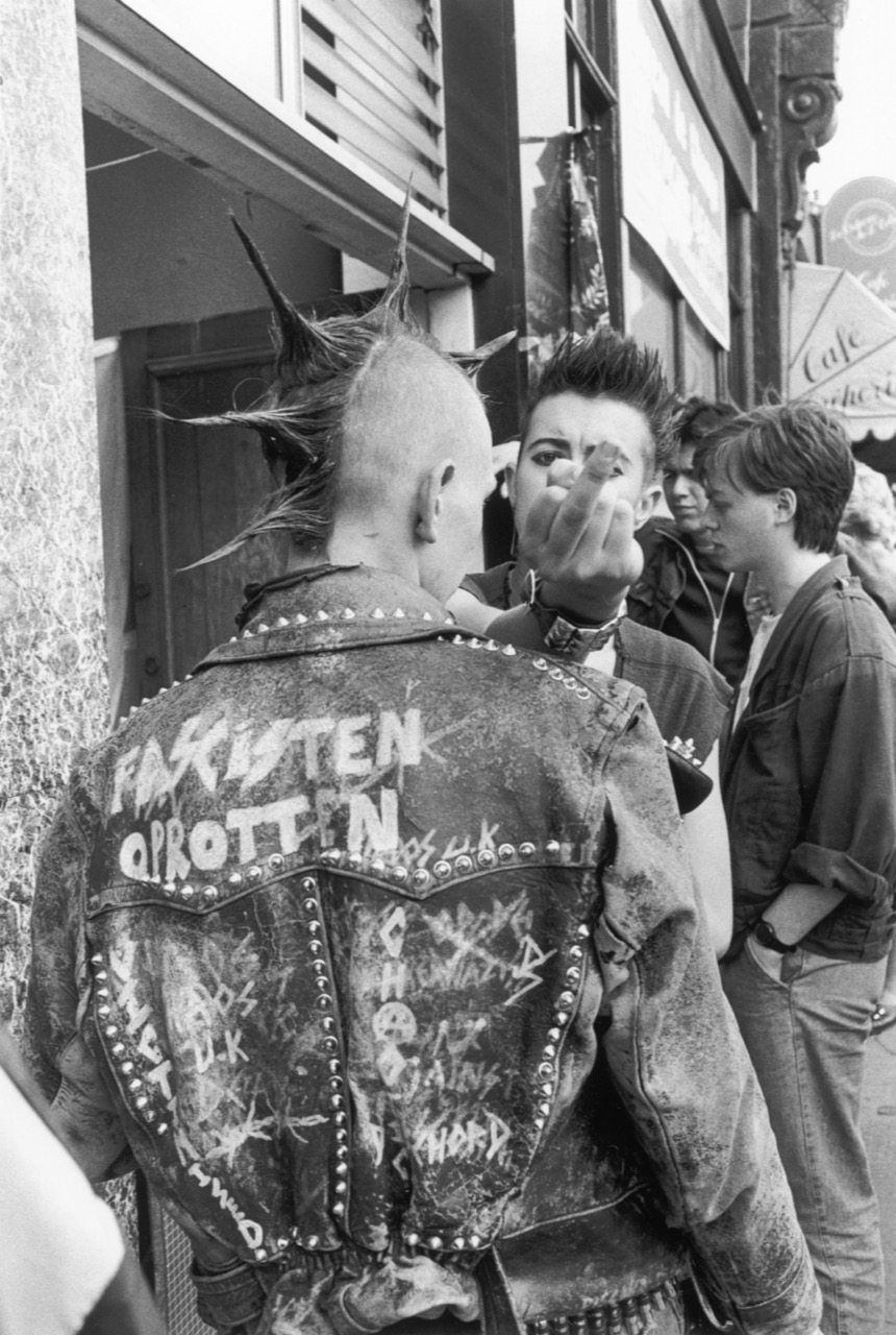 black and white photo of two punks, one giving the camera the finger