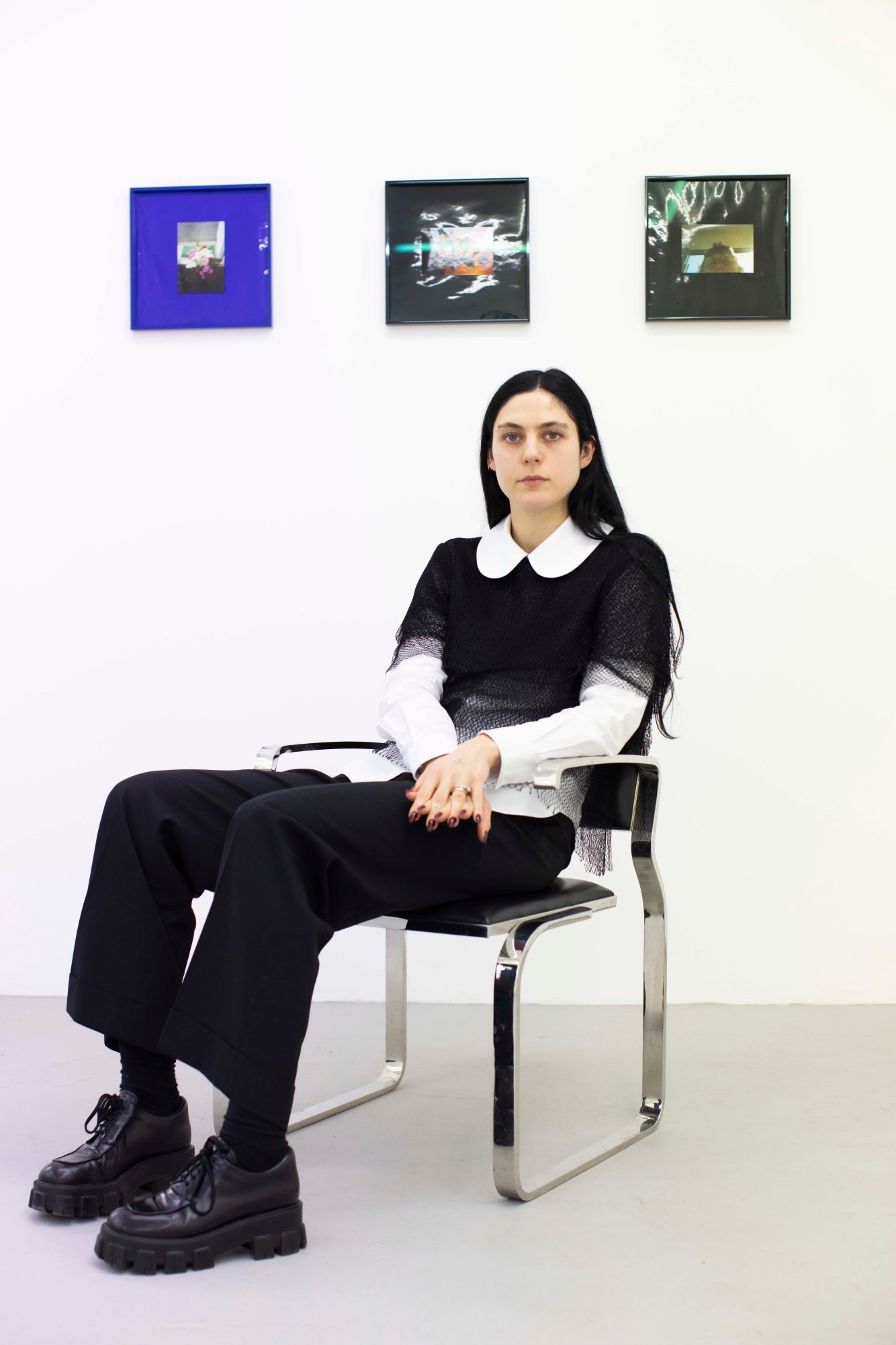 rose eaton sitting in a chair in front of art in her london gallery